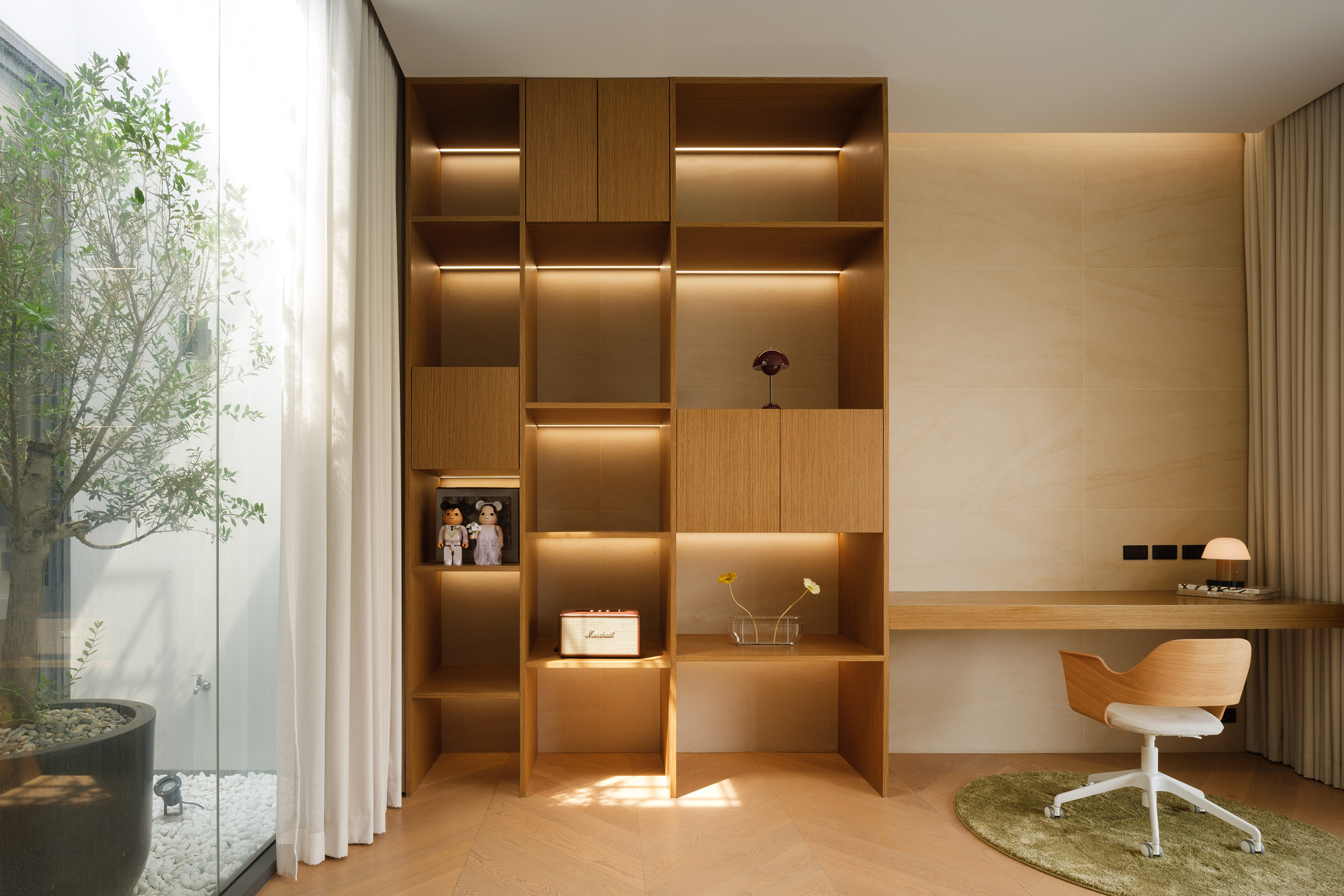 Study nook with illuminated timber shelving and view to the planted courtyard through glass