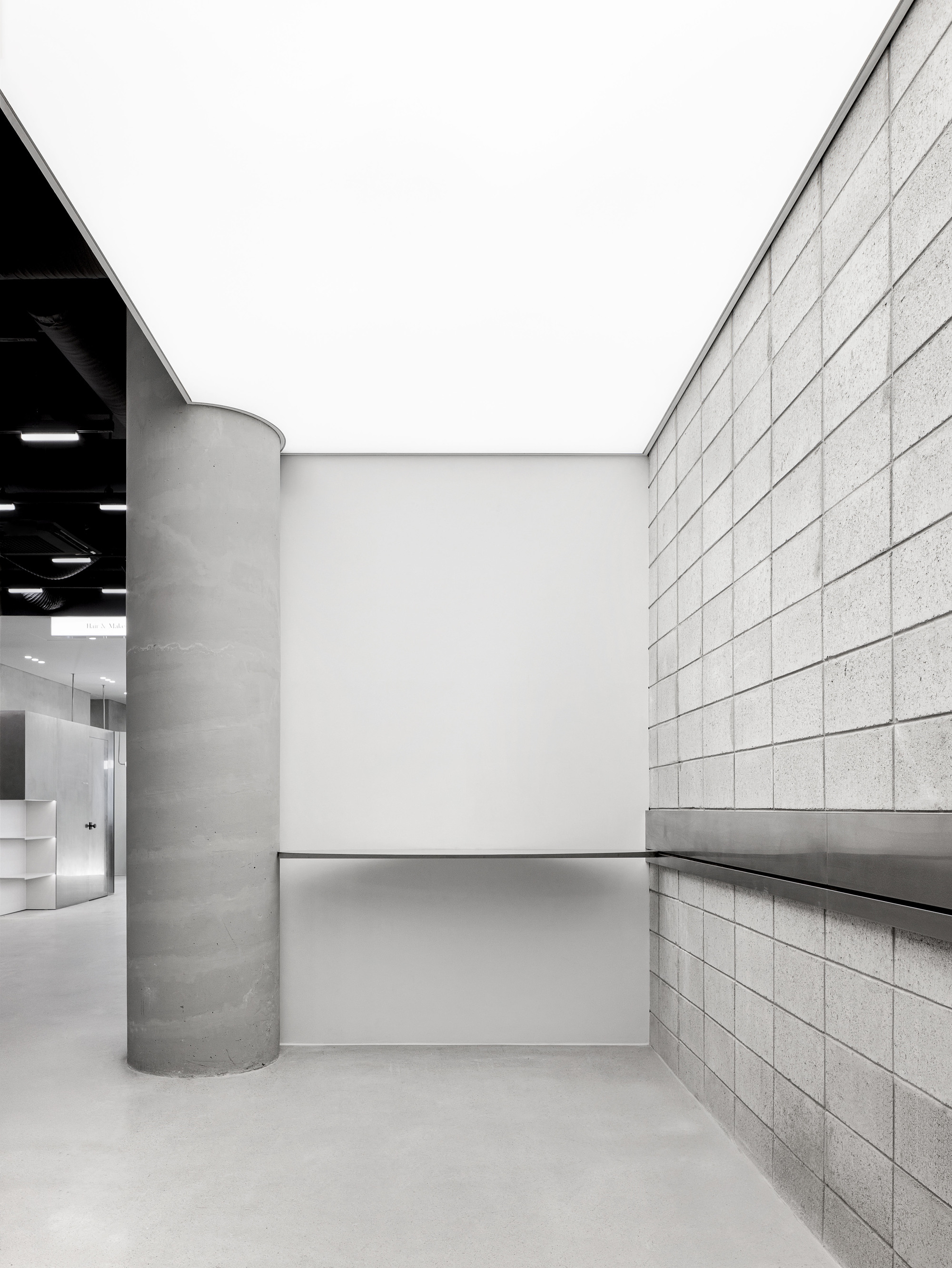 Open courtyard space framed by concrete column, gridded block wall and white recessed ceiling