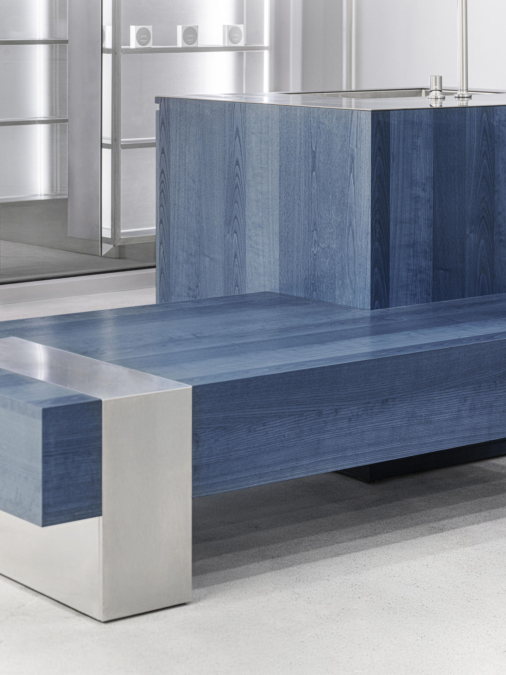 Close-up of blue wood bench with stainless steel base beside matching counter unit