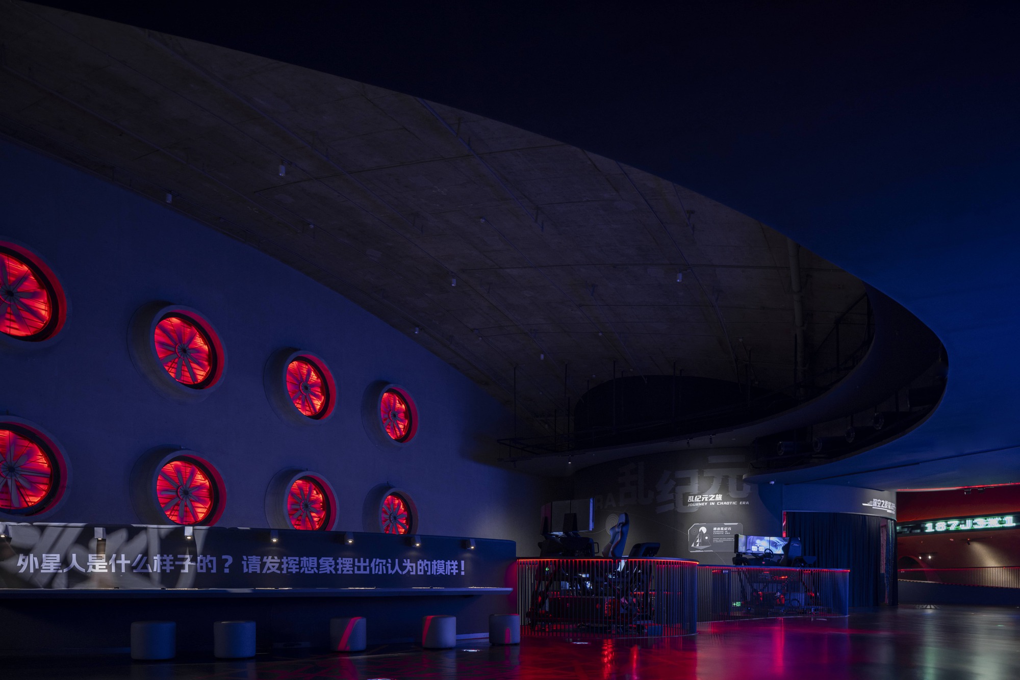 Interior exhibition hall with curved soffit and red illuminated circular ventilation grilles at twilight