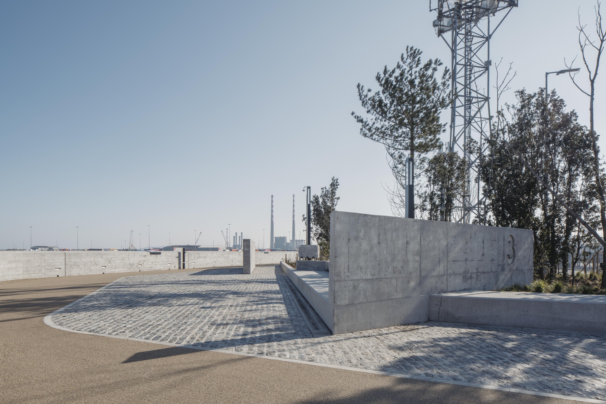 Curved concrete seating walls and paved plaza with communication tower and bare trees