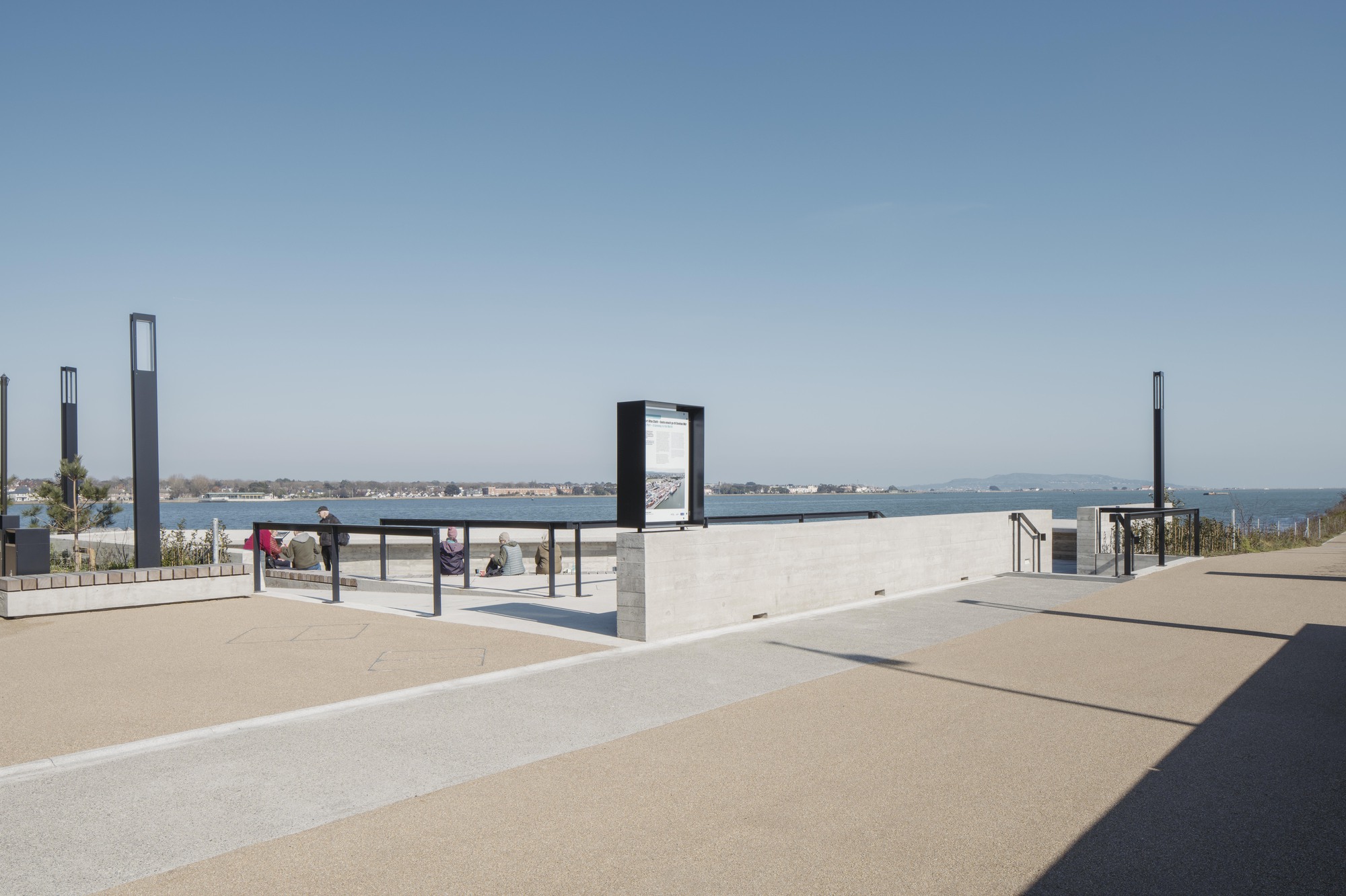 Paved plaza with information kiosks and concrete walls opening to views of the harbor