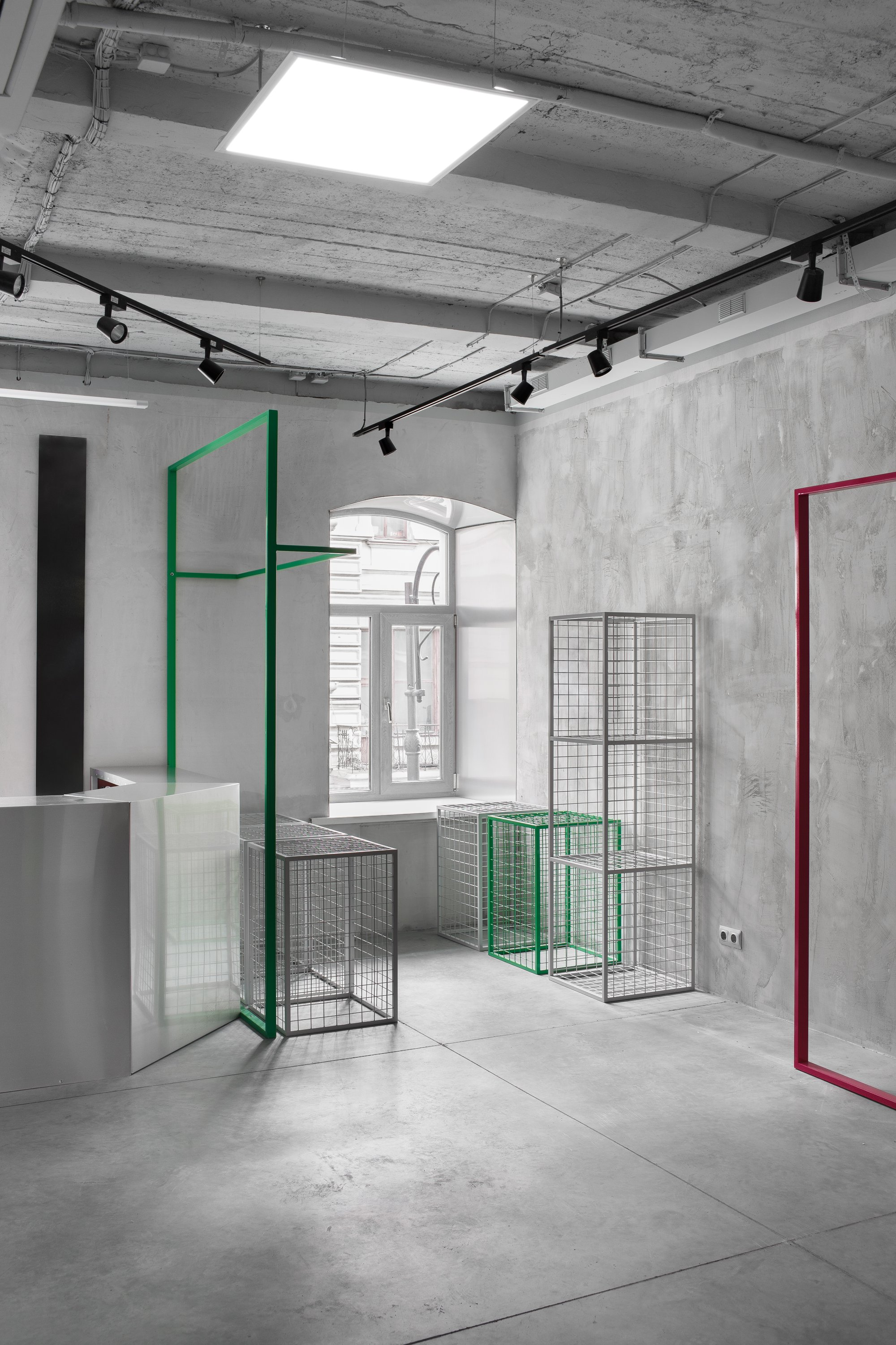 Minimal industrial showroom with modular metal display frames and exposed concrete finishes.