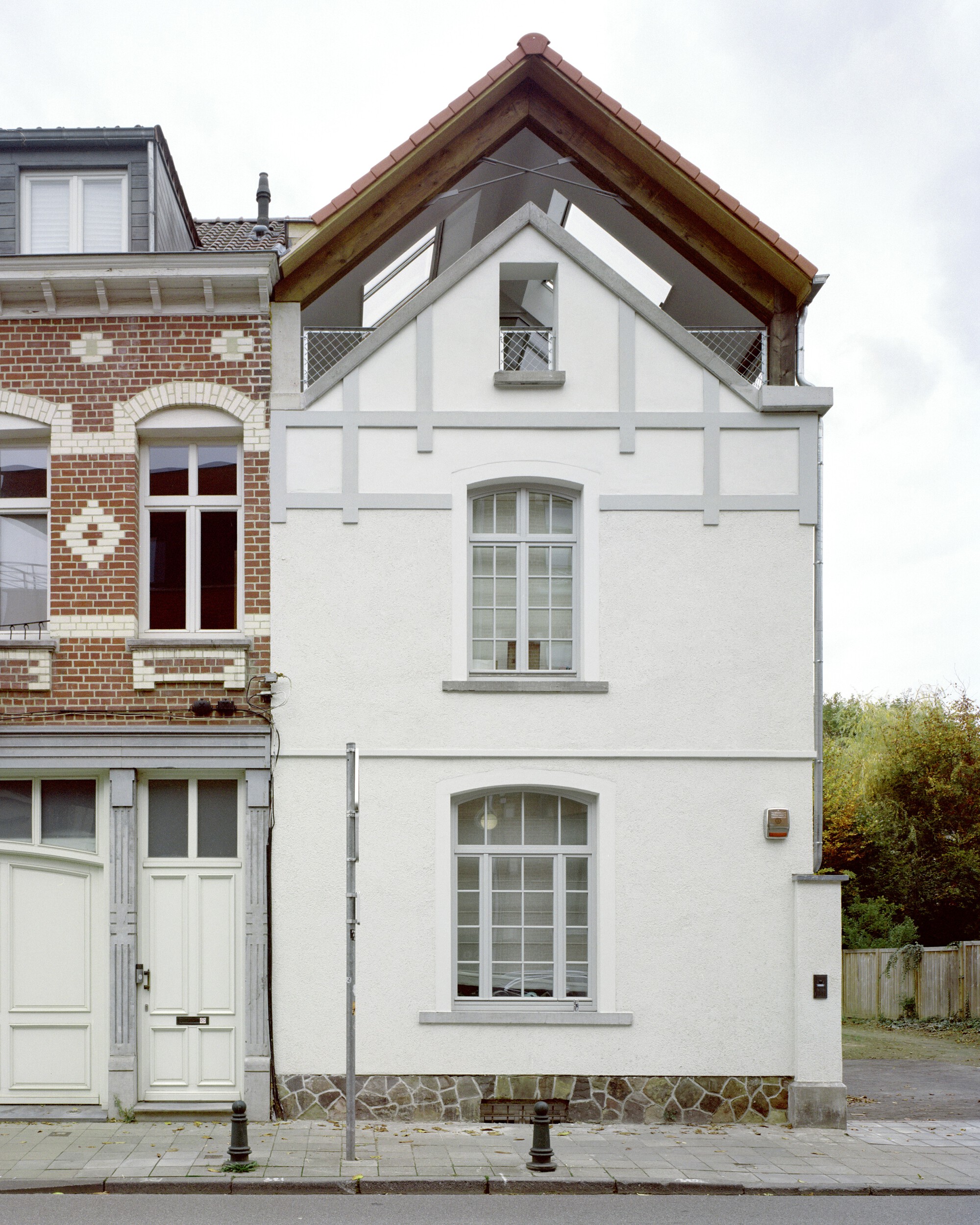 Street facade of white rendered townhouse with arched windows and terra cotta tiled gable roof