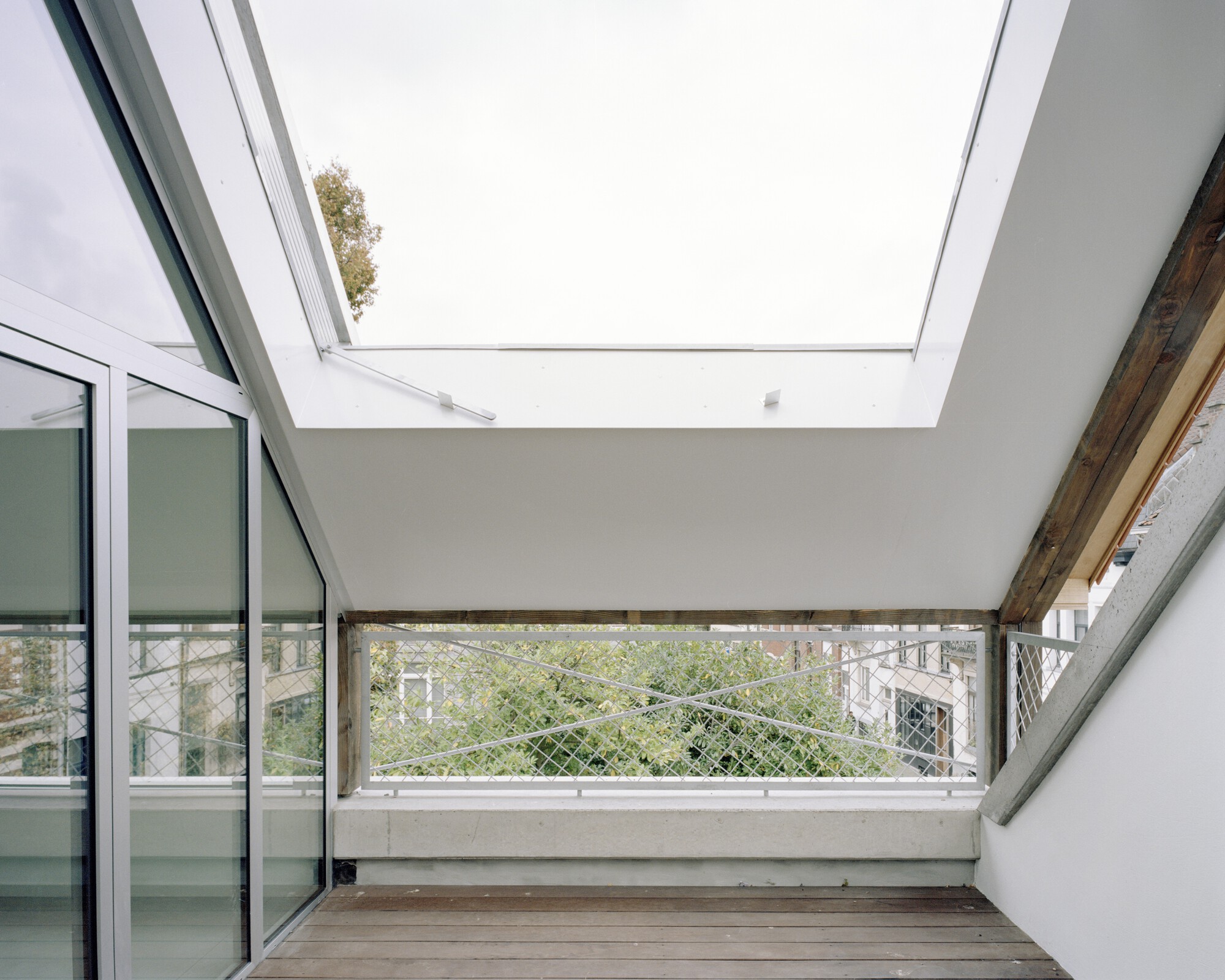 Open skylight above a terrace with wire mesh railing and sliding glass doors