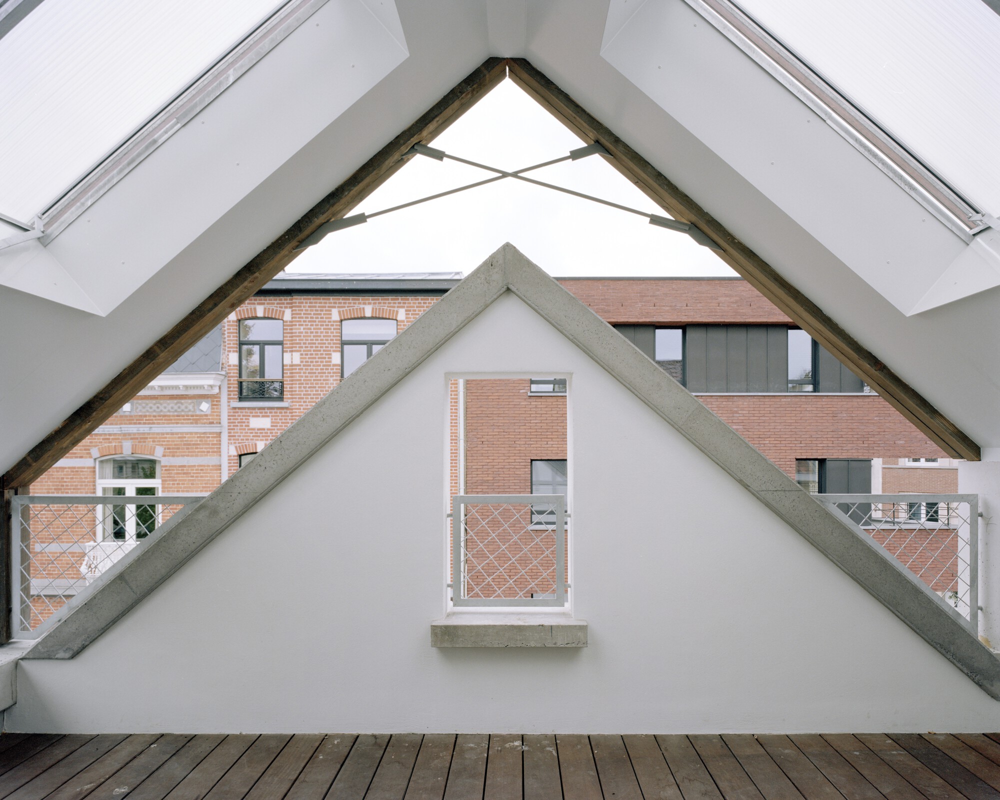 Exposed timber roof truss framing a gable window overlooking a brick courtyard