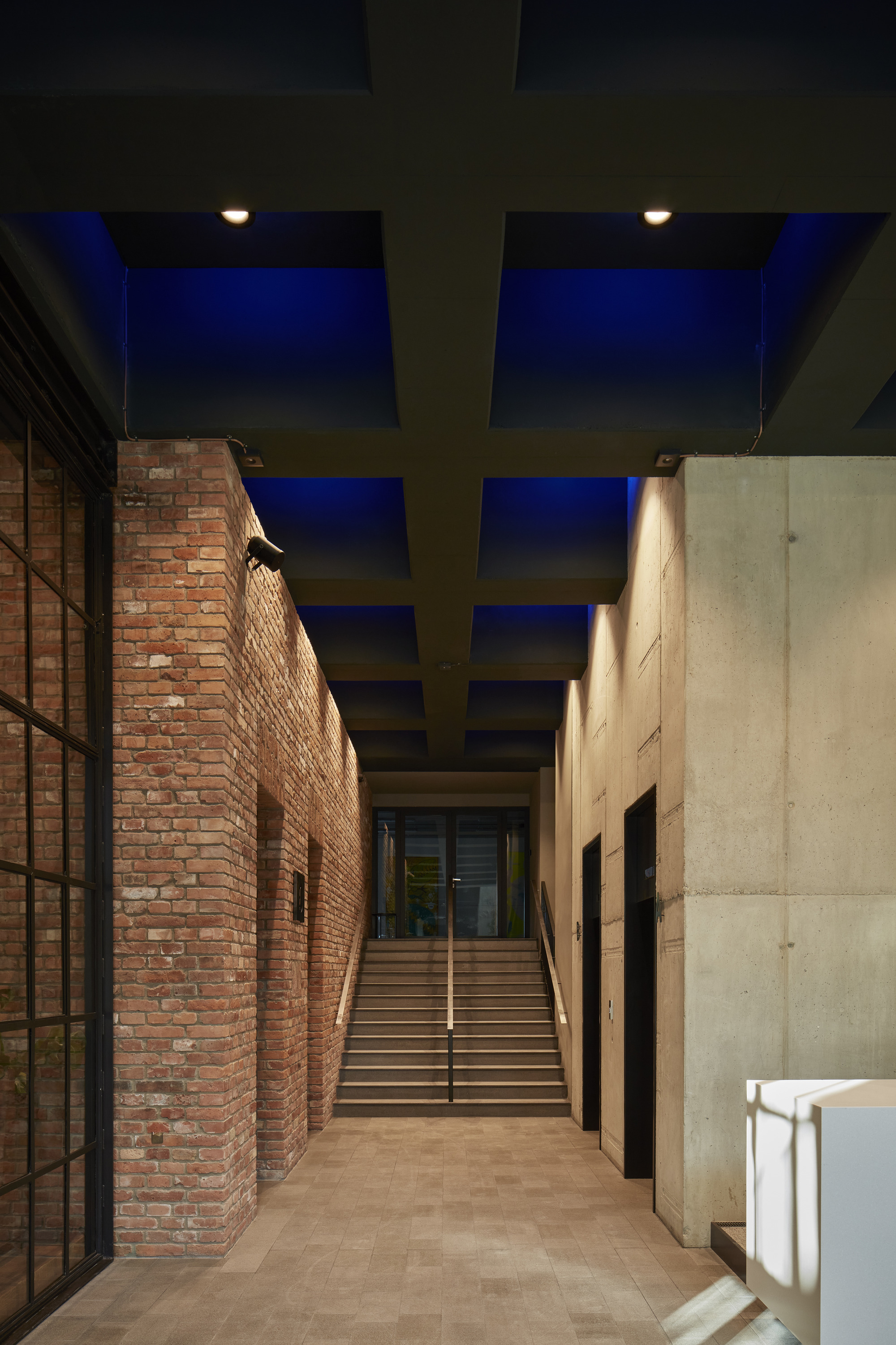 Covered passageway between brick and concrete walls leading to a staircase at twilight