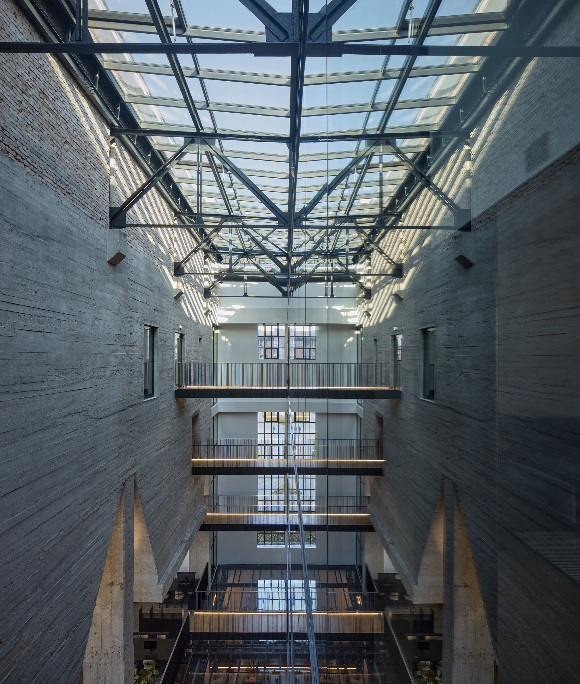 Upward view through the atrium showing stacked walkways and the steel truss skylight above
