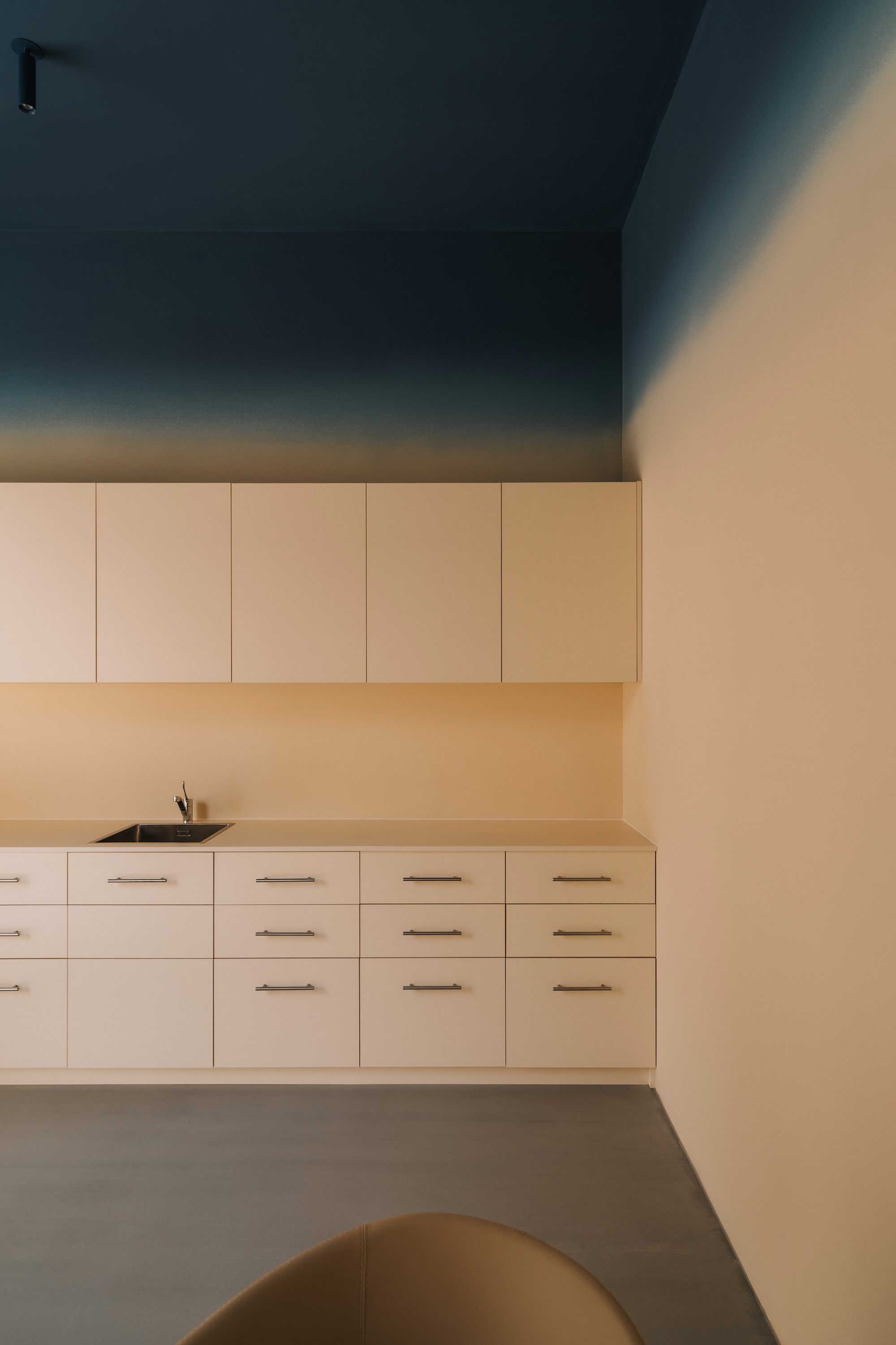 Wall-mounted cabinets with light wood countertop under a deep teal ceiling