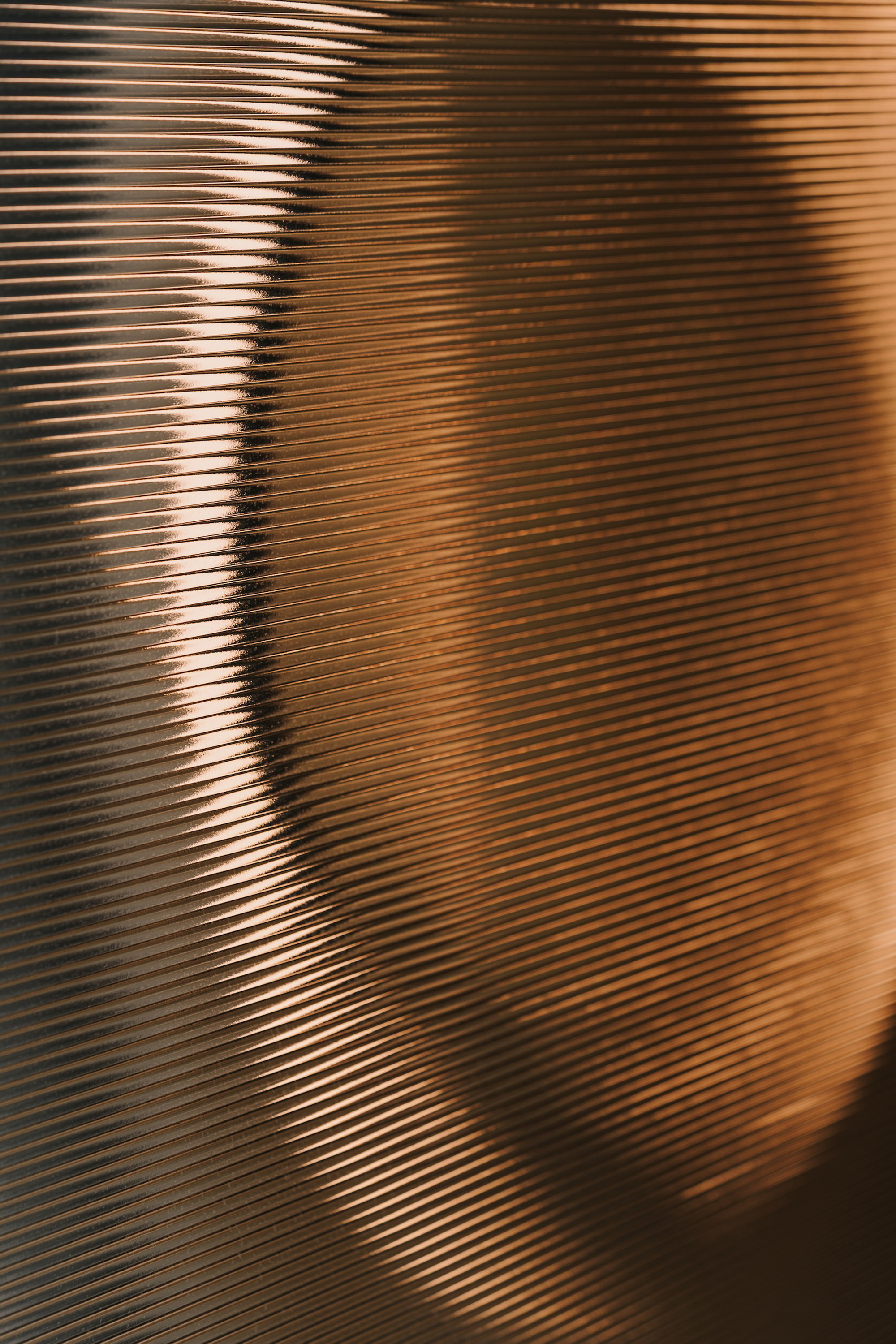 Close-up of corrugated metallic screen with horizontal ribbing catching warm afternoon light