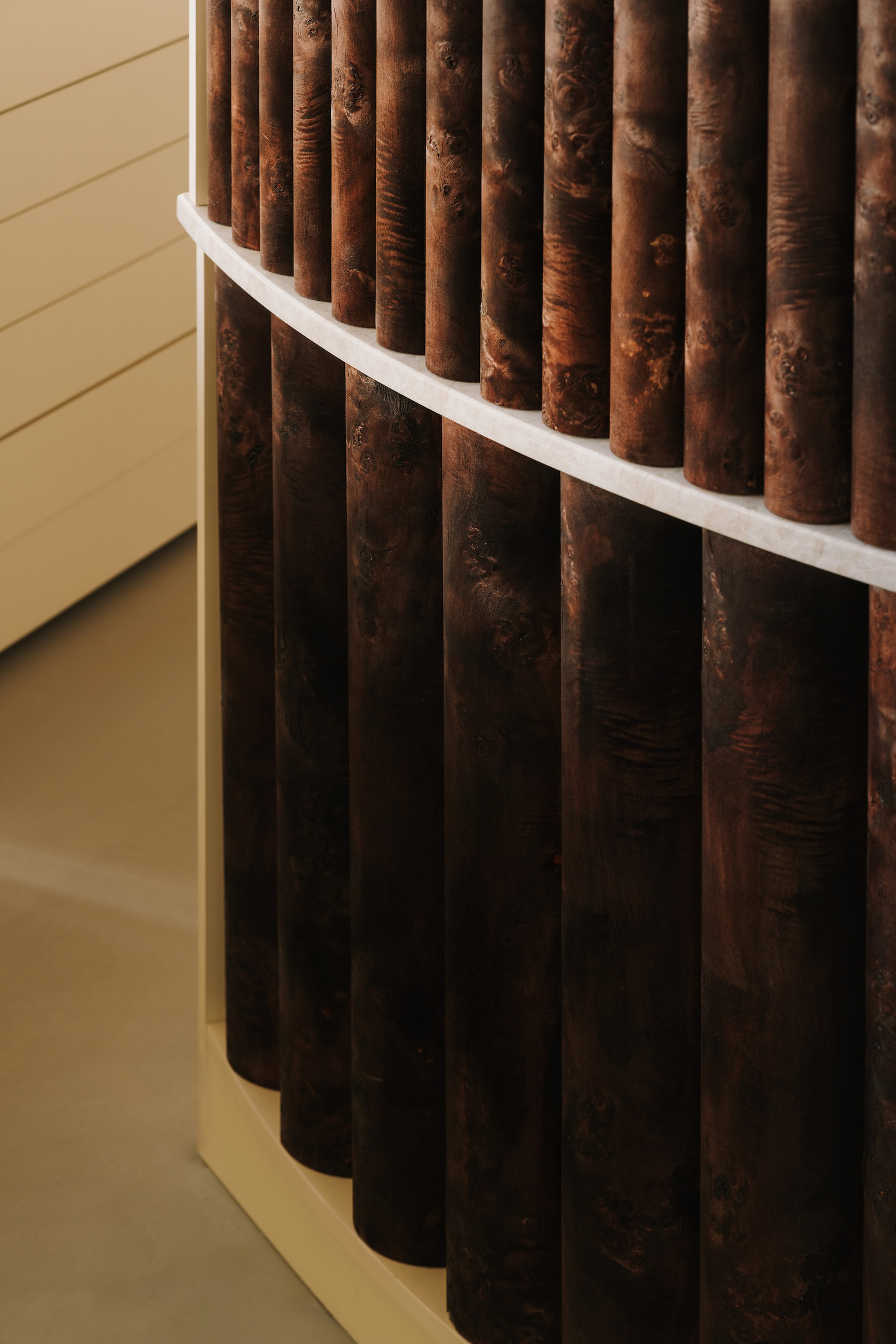 Detail of weathered steel tubes intersecting a white horizontal bar and yellow wall plane