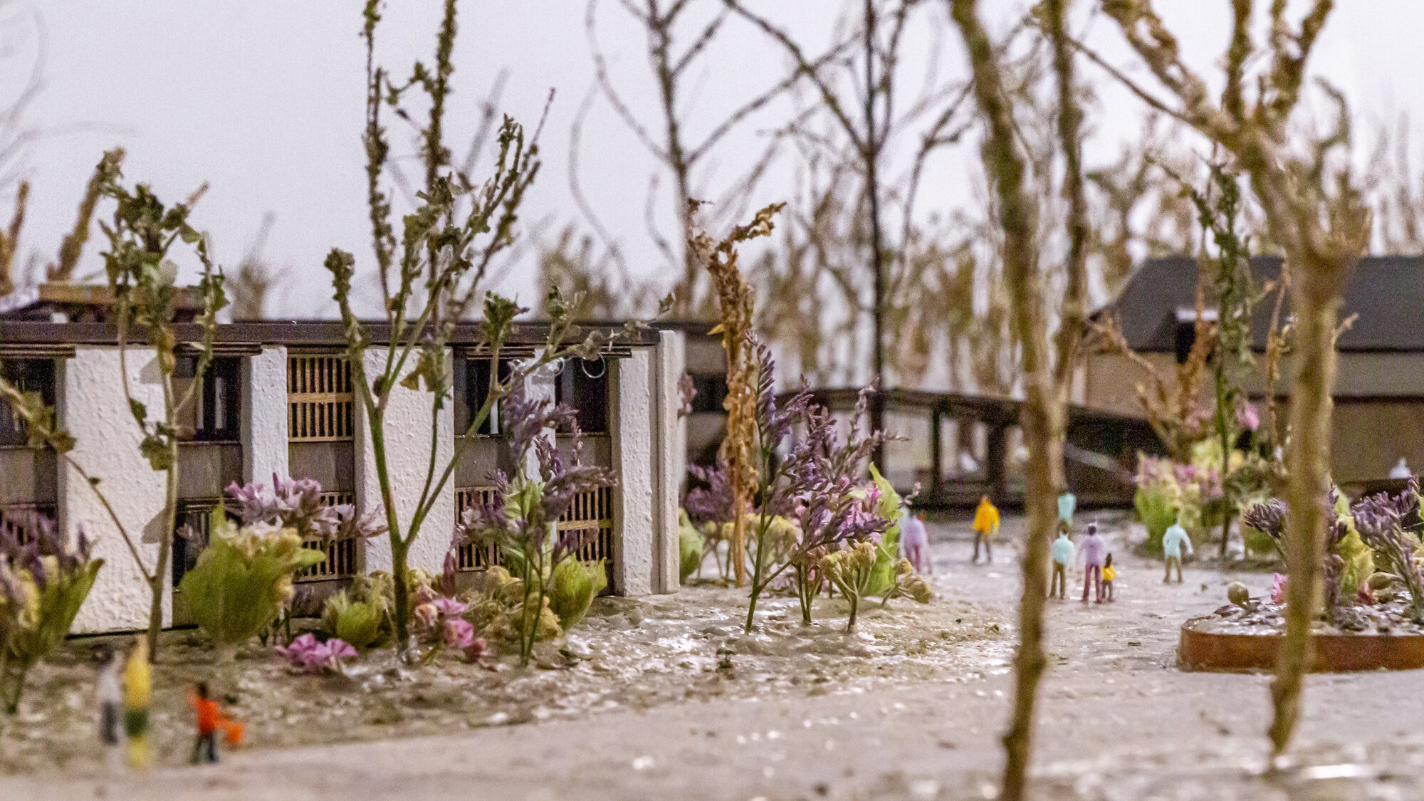 Physical model detail showing courtyard with scale figures and cherry blossom trees among residential blocks
