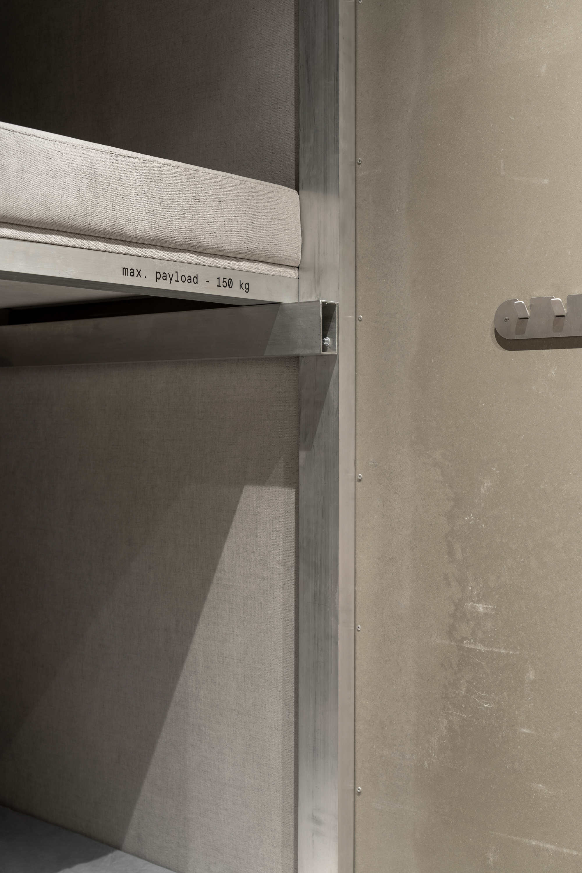 Industrial shelf unit with maximum payload label against concrete wall with exposed fasteners