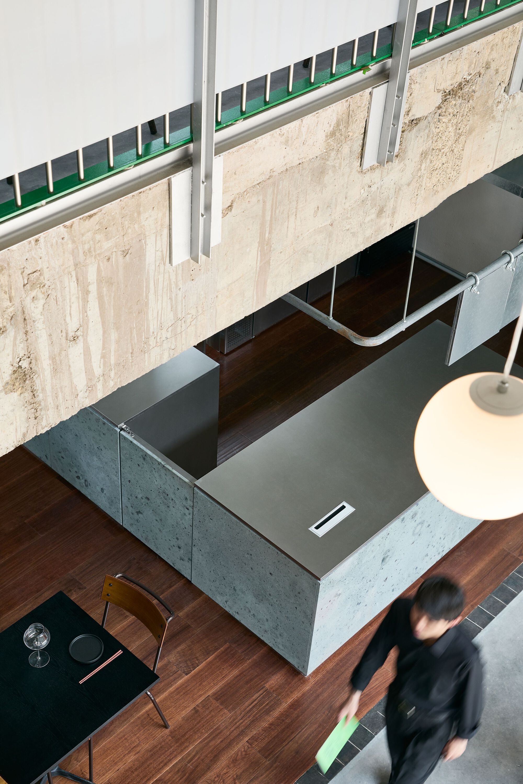 Top-down view of the concrete reception counter with walnut trim and a person passing below