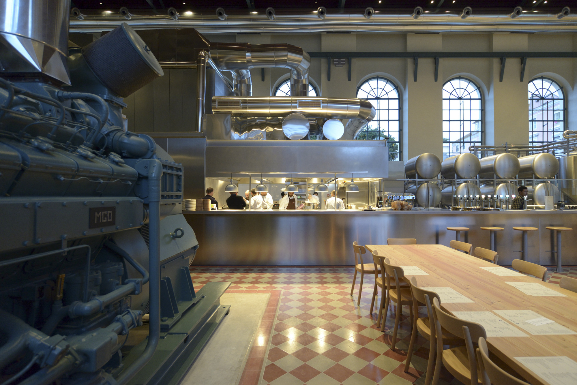 Interior view of the double-height dining space with stainless steel kitchen counter and original chequered tile floor