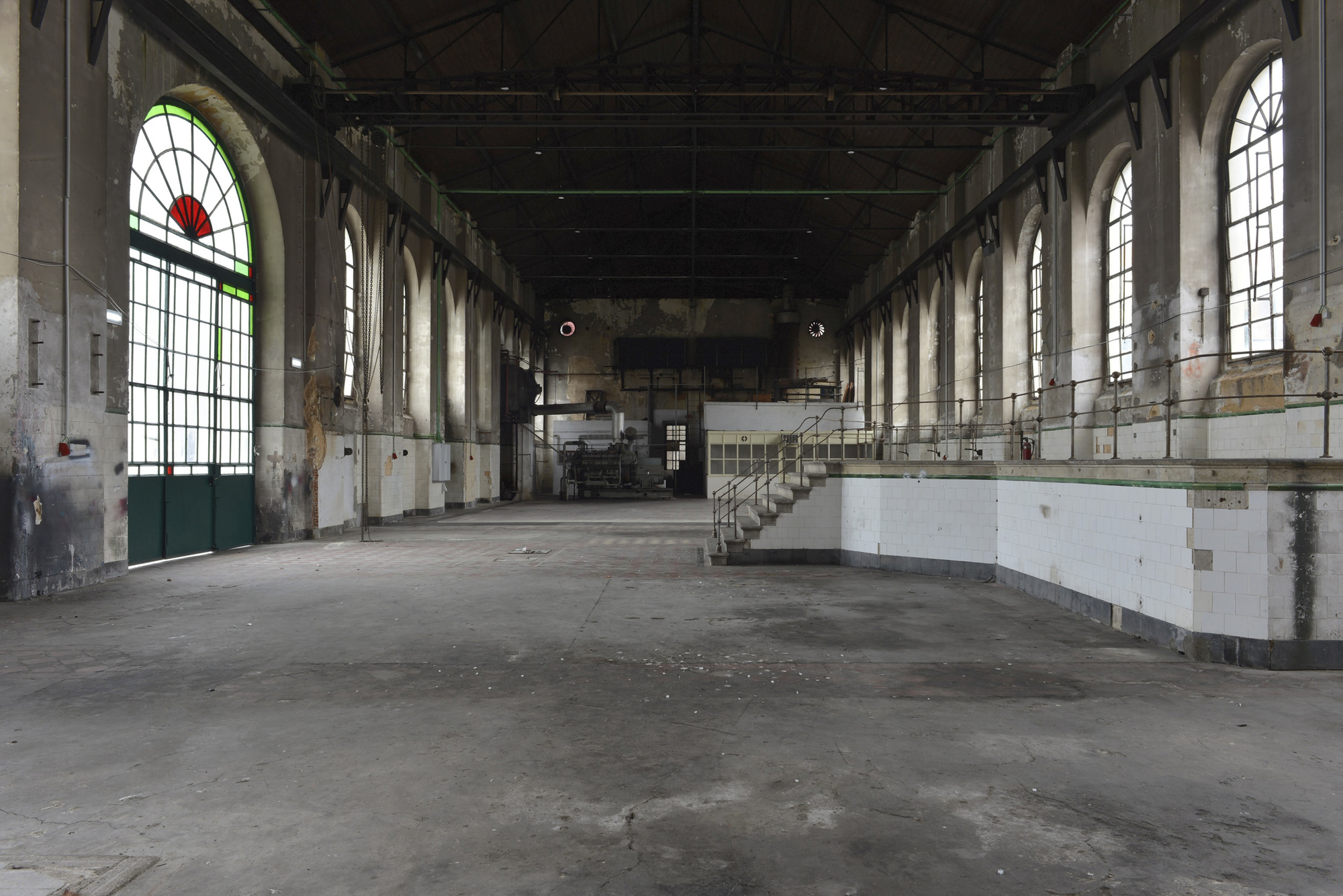 Interior view of the vacant hall with arched windows and remnant tile wainscoting before adaptive reuse
