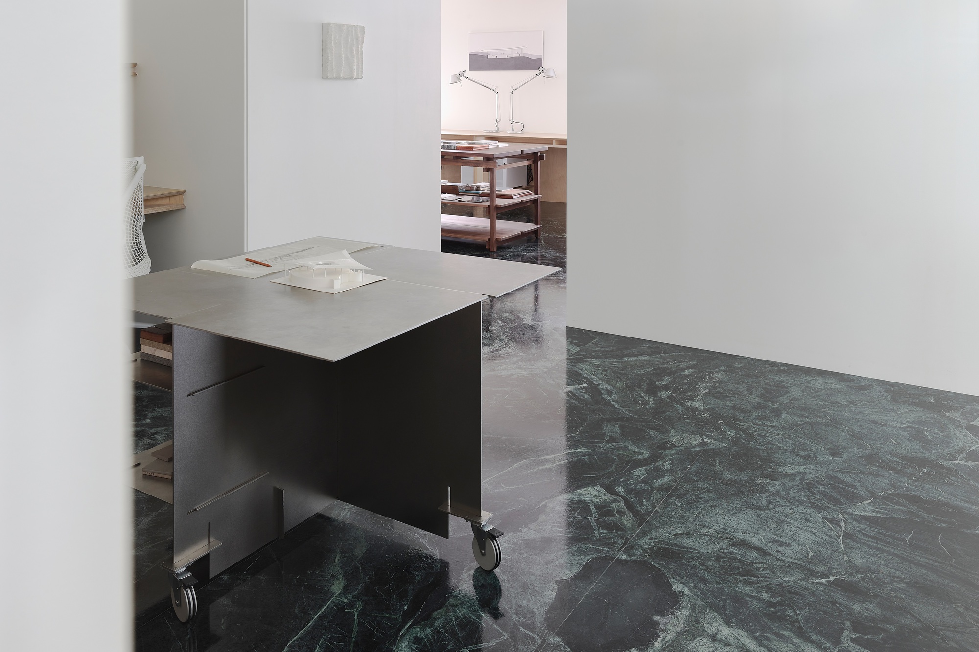 This architectural image showcases a minimalist studio space with a focus on clean lines and material contrast. The room features marble flooring, white walls,