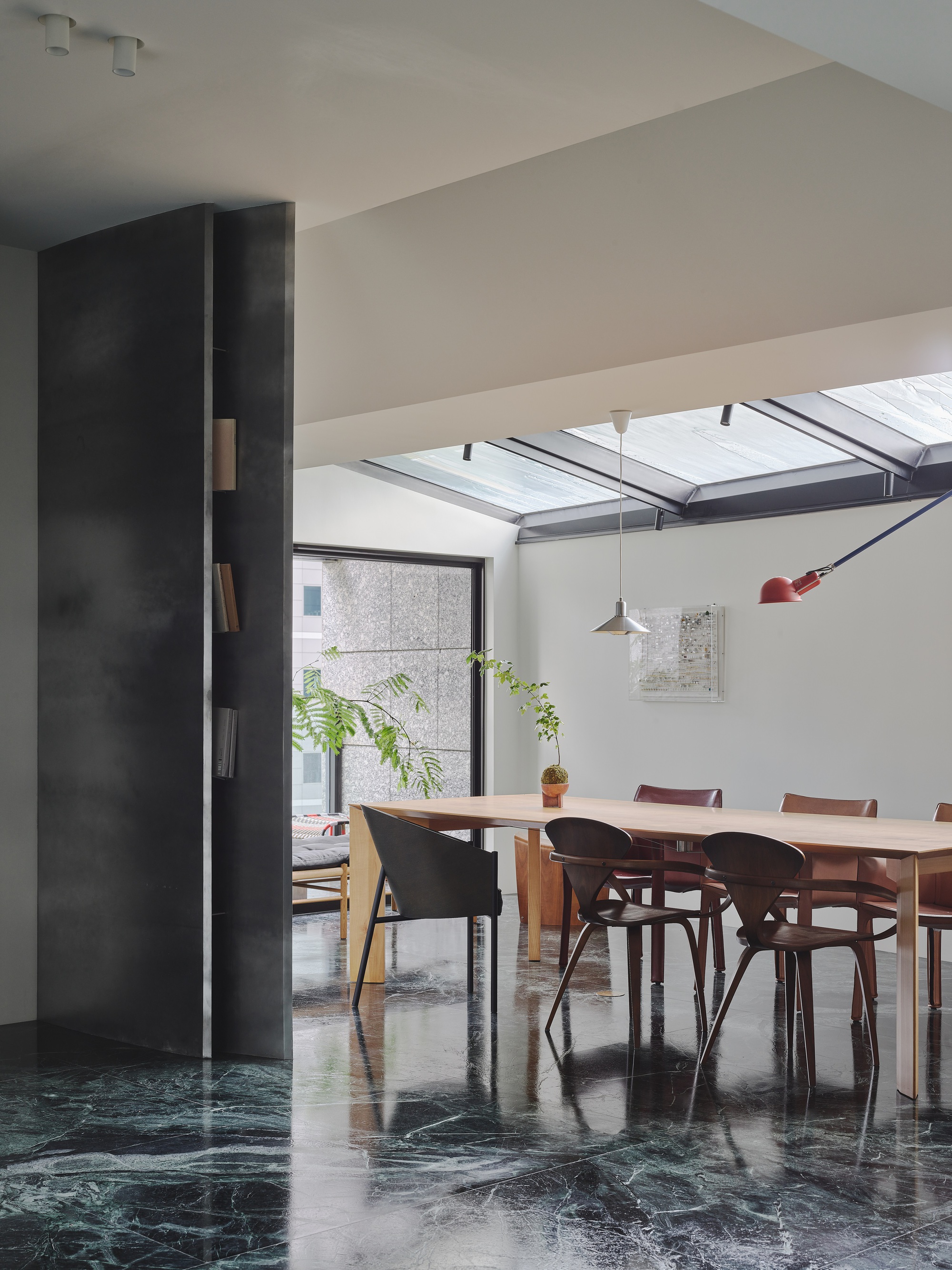 This architectural image showcases a modern dining room with a minimalist aesthetic. The space features a long wooden dining table surrounded by stylish chairs,