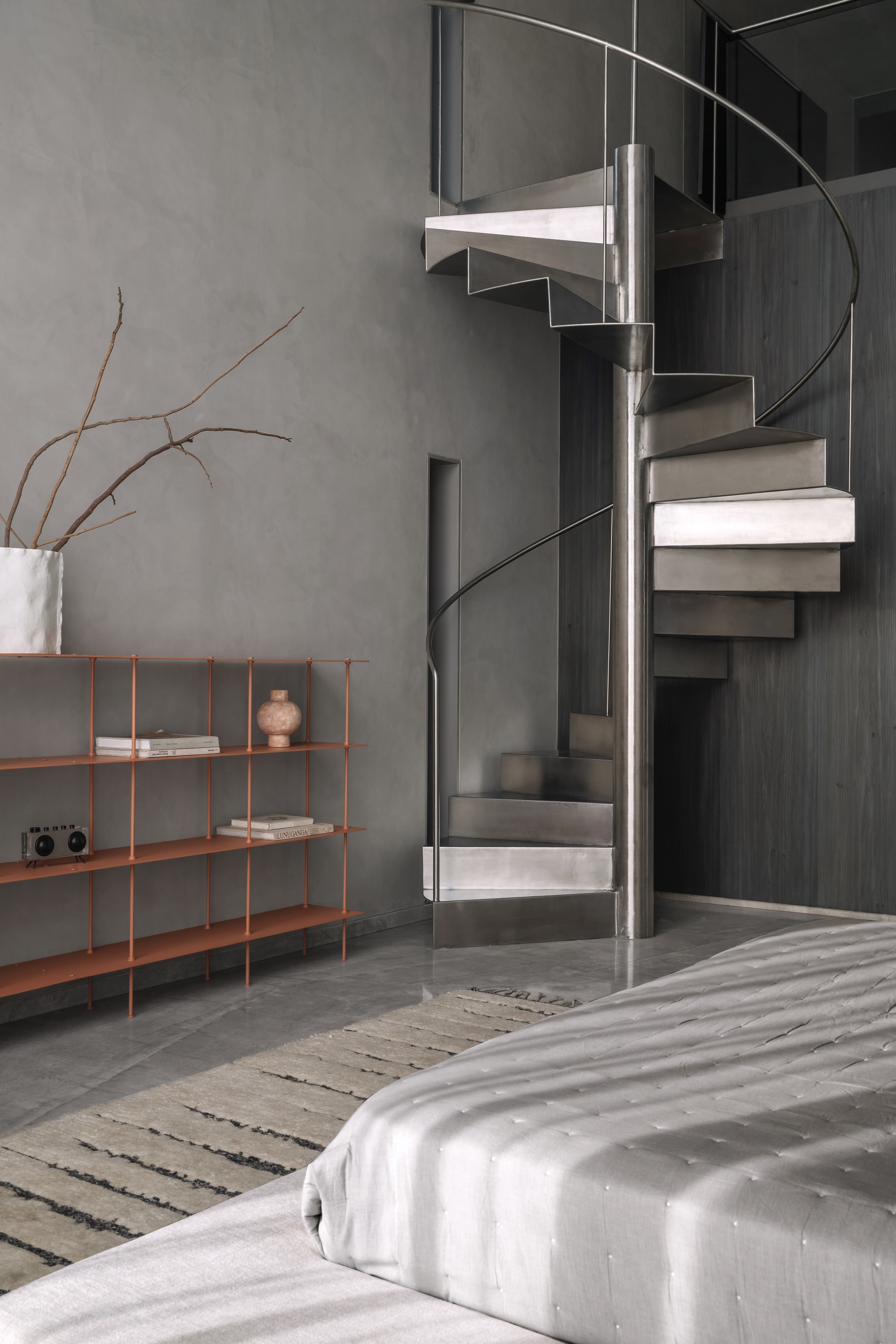 Close-up of circular spiral staircase with metal treads and handrail against dark paneled wall
