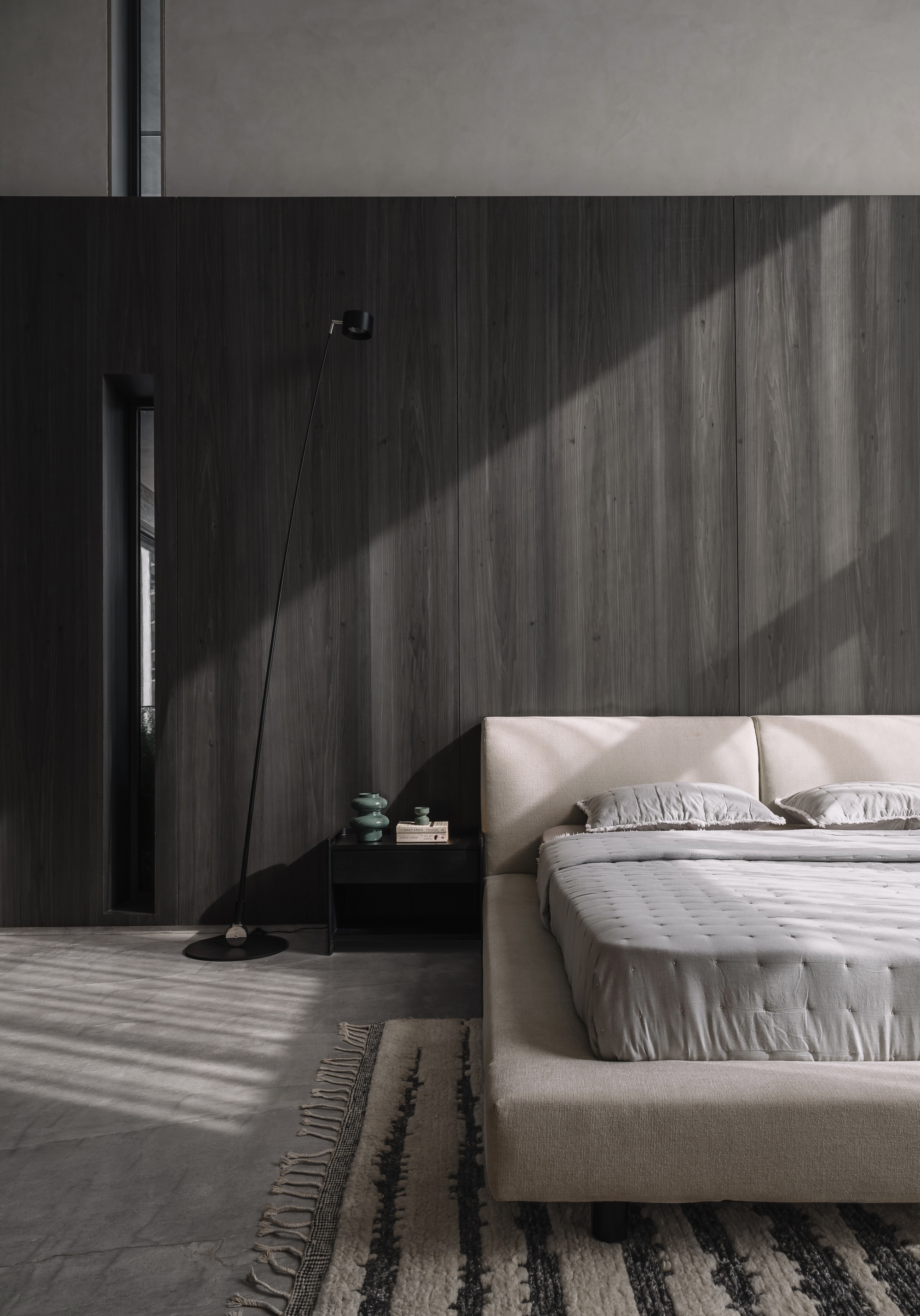 Dark wood wall in a bedroom with striped shadows cast by natural daylight through unseen blinds