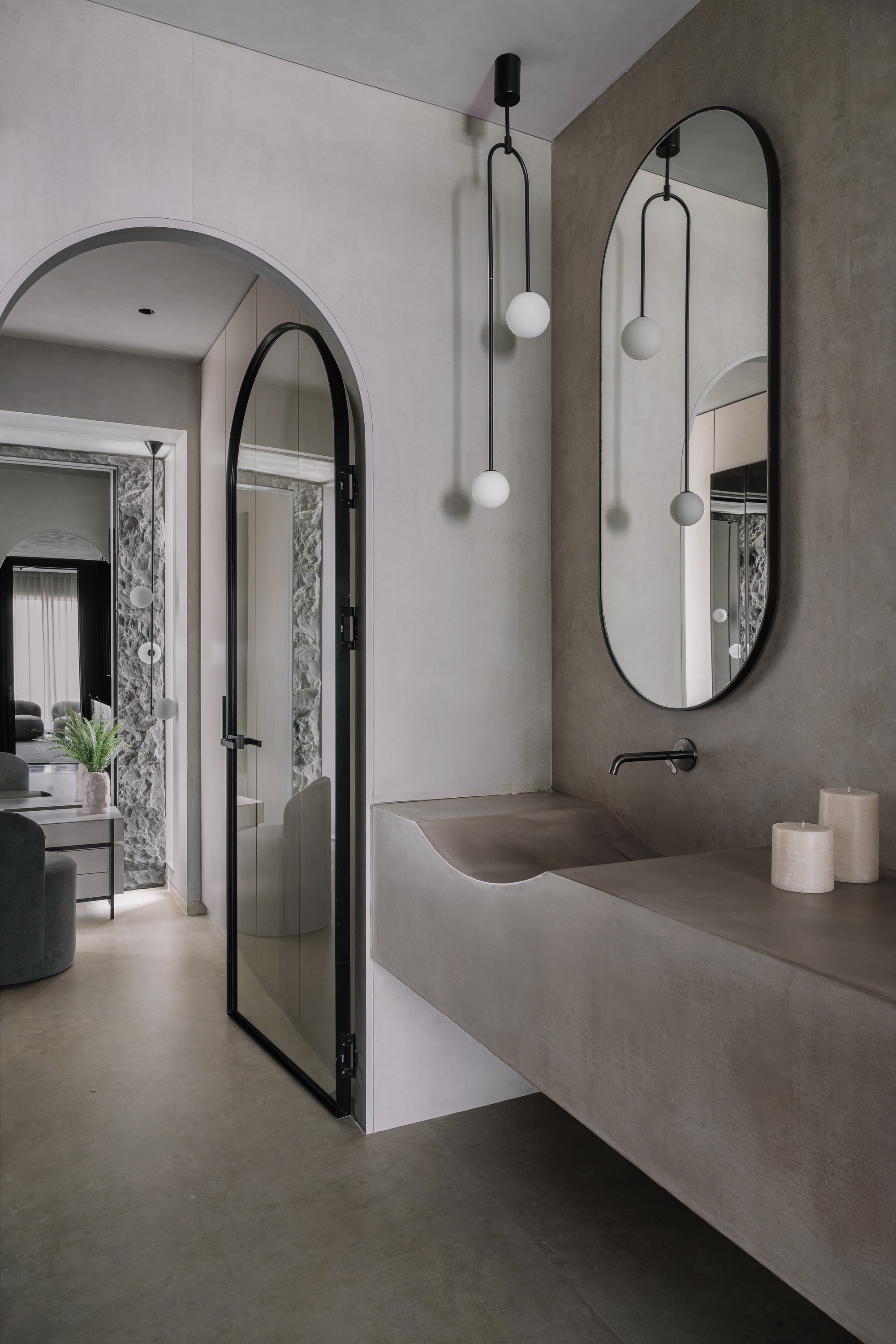 Bathroom vanity with integrated sink in grey stone beneath an arched doorway and pendant lights