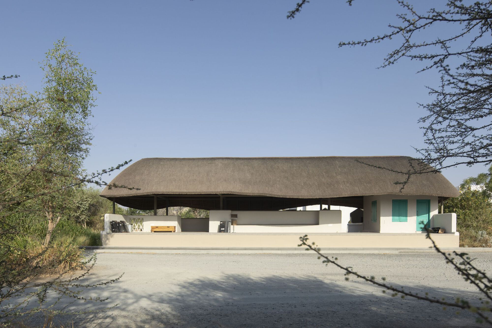 Front view of the sweeping thatched roof canopy floating above white rendered walls framed by bare trees