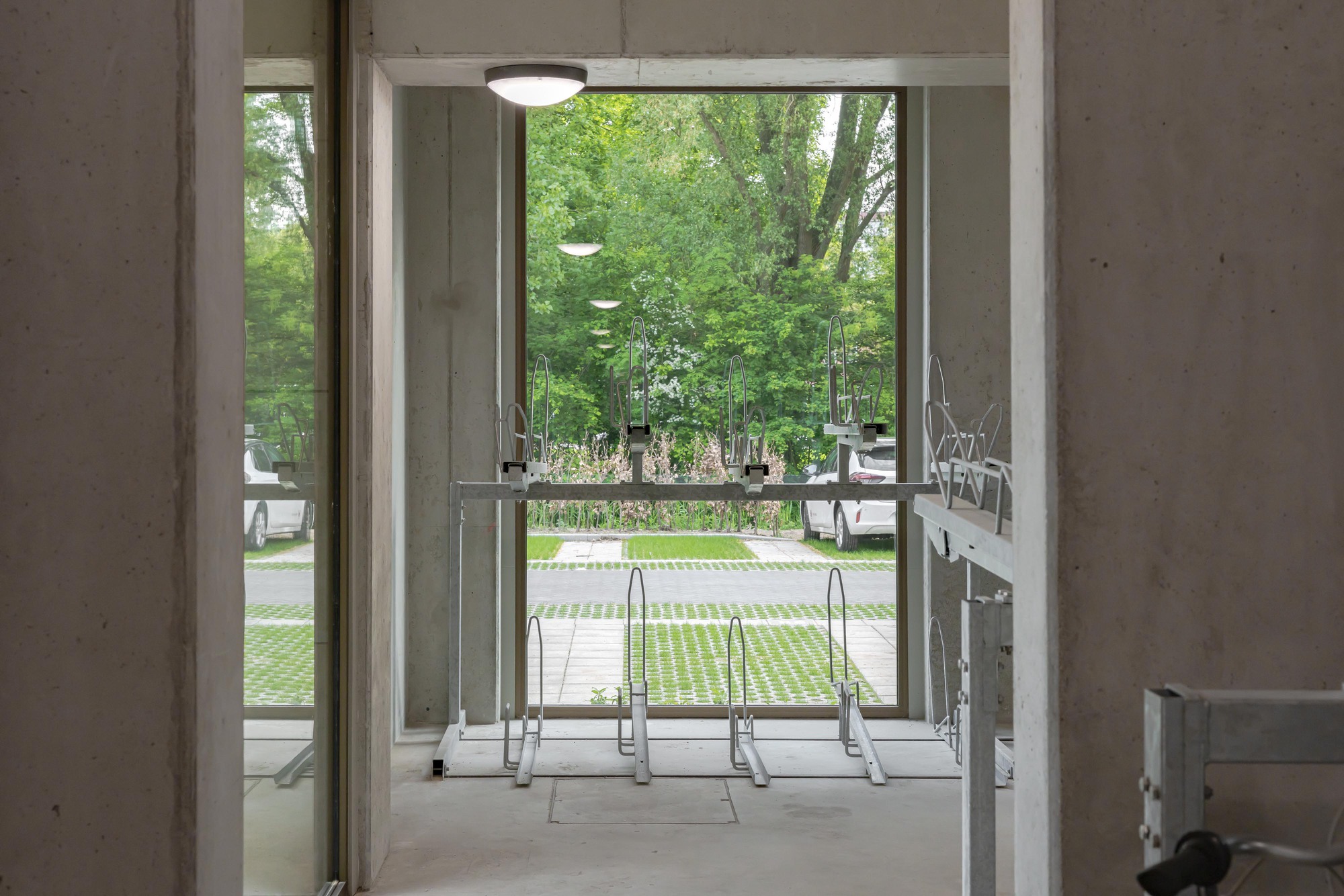 Glass table and chairs in concrete interior opening to landscaped courtyard with planted beds