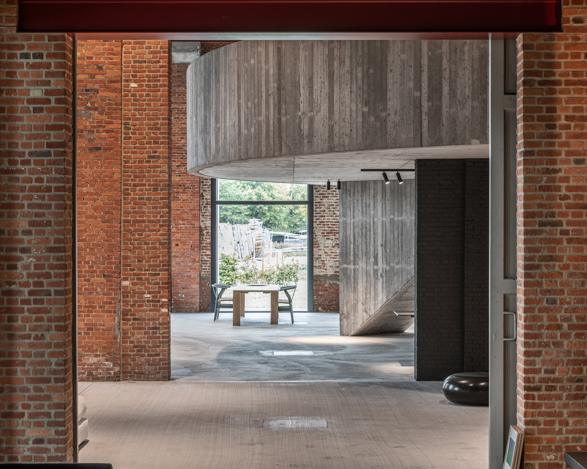 Interior view through exposed brick walls toward a cantilevered concrete volume and courtyard beyond