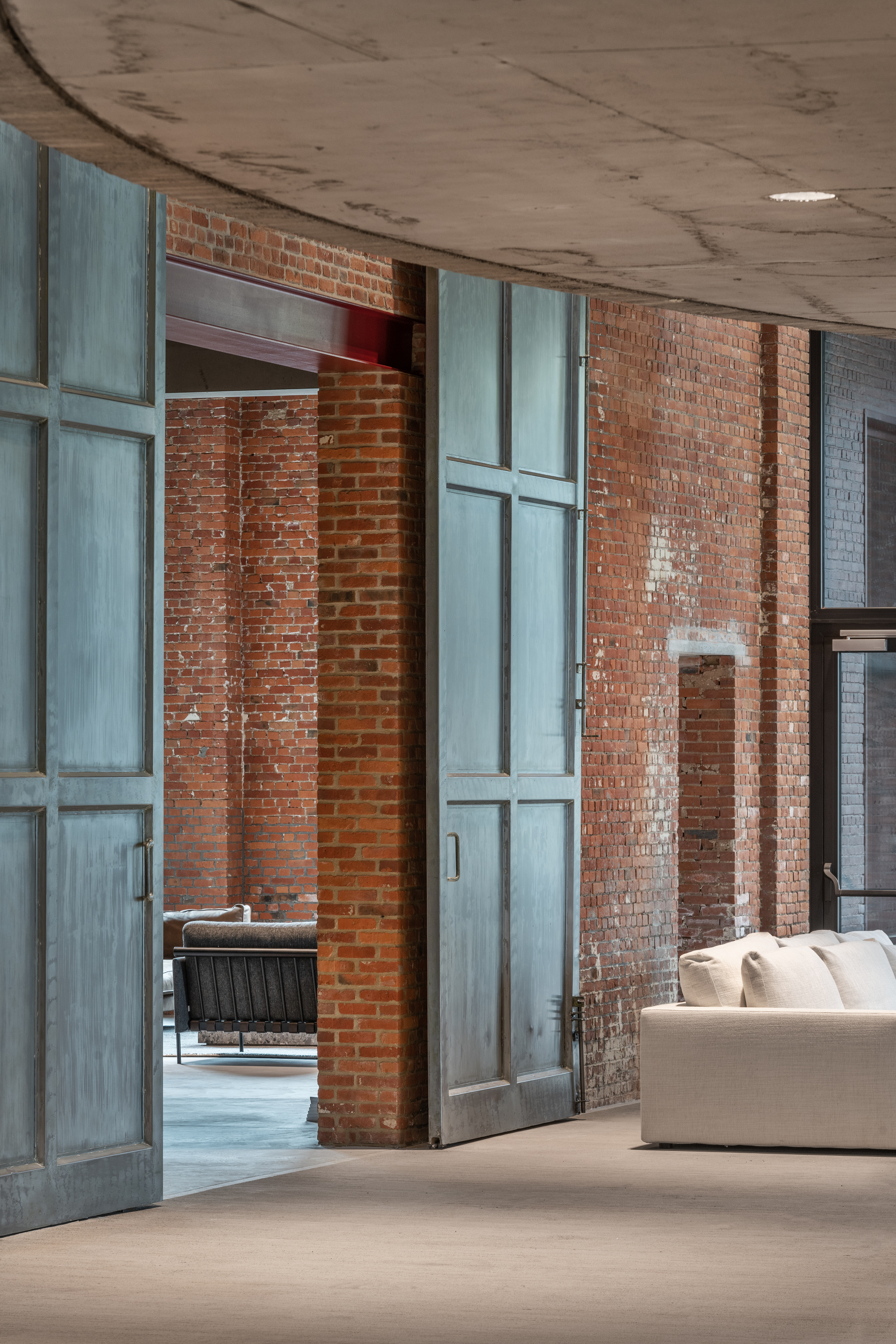 Tall steel-framed sliding doors with patinated finish between exposed brick piers