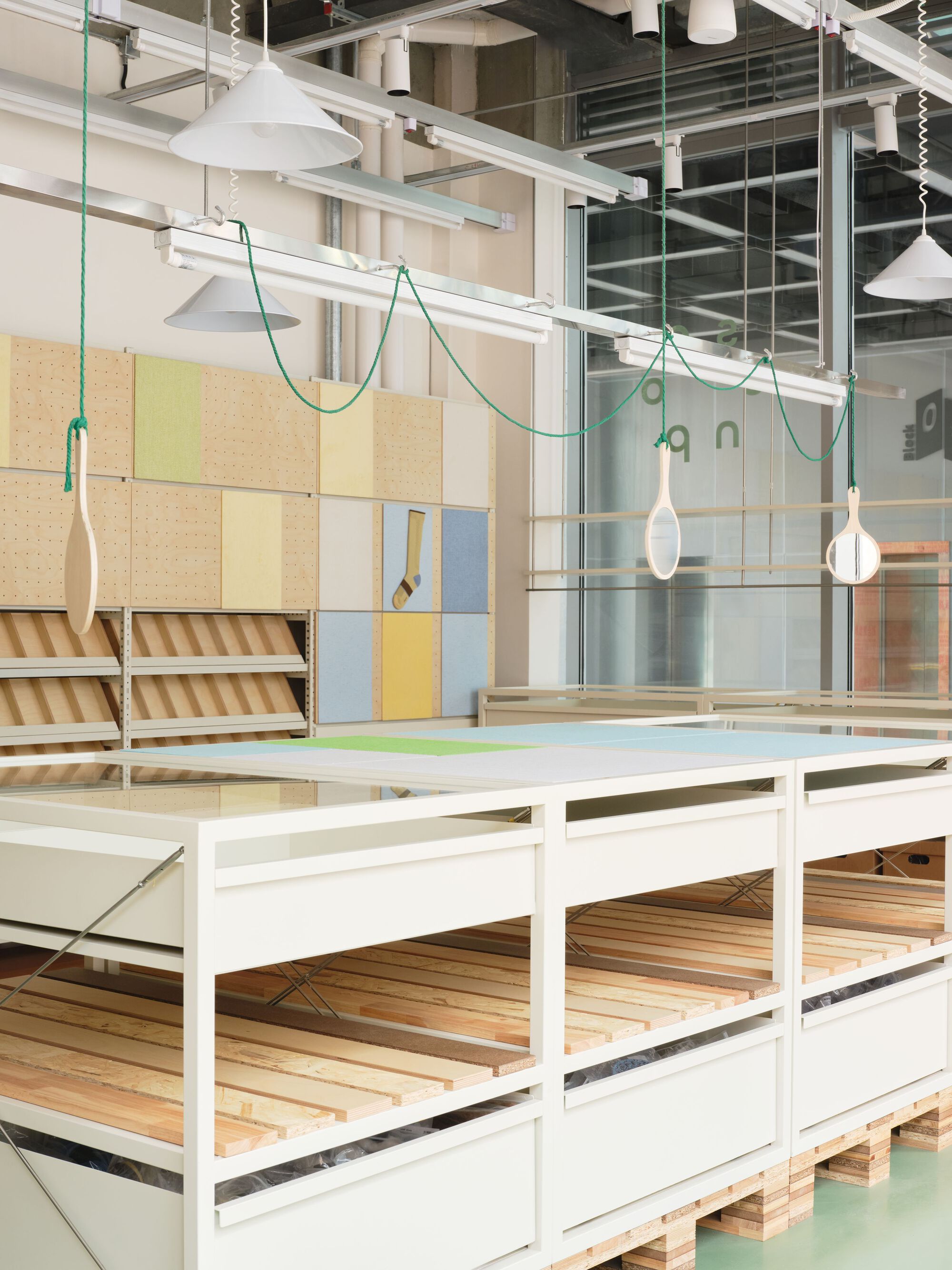 White framed display platforms beneath pendant lights suspended on green braided cords