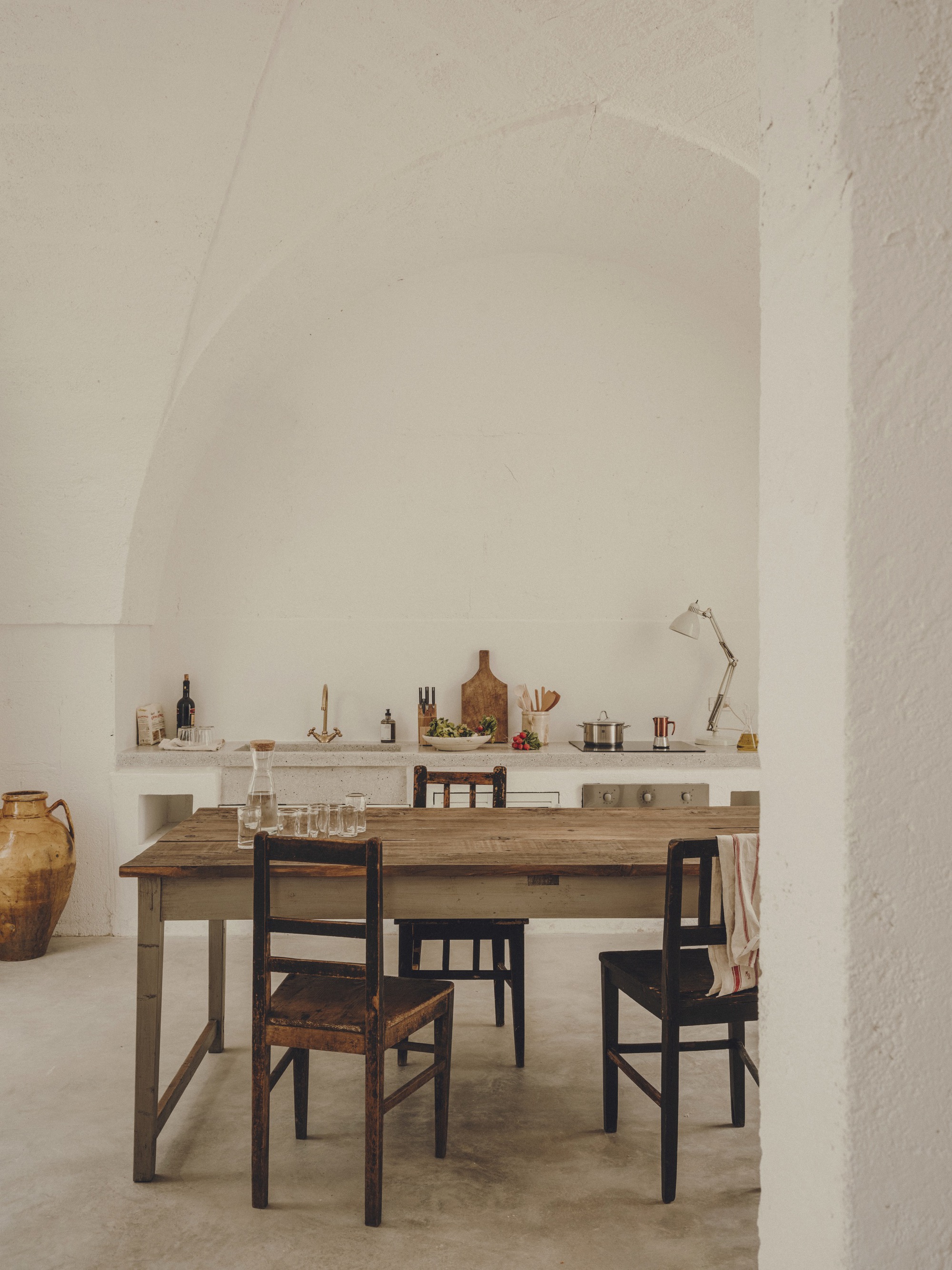 Dining area with timber table and mismatched chairs beneath a vaulted white plaster ceiling