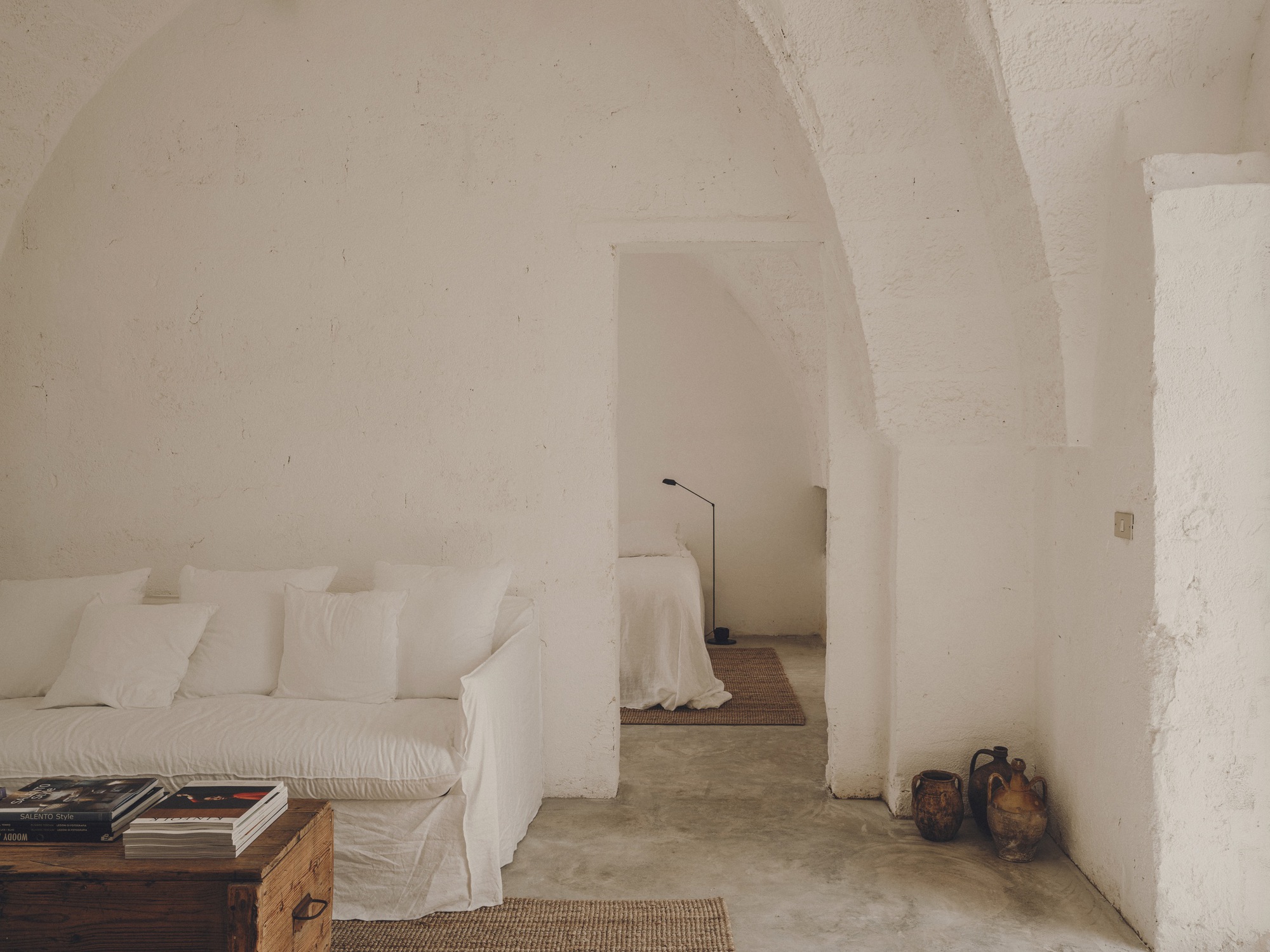 White plastered interior with vaulted arches connecting seating area to adjacent sleeping space