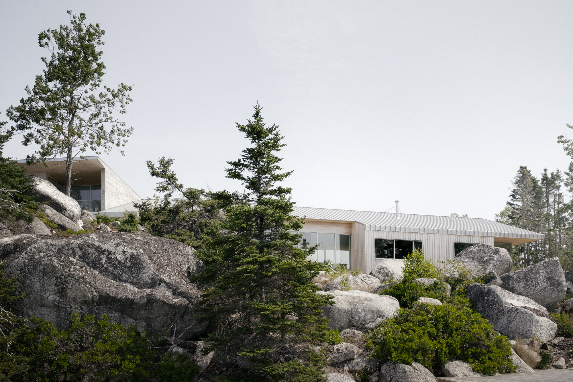 Low-slung profile with corrugated metal roof nestled among granite boulders and evergreen trees