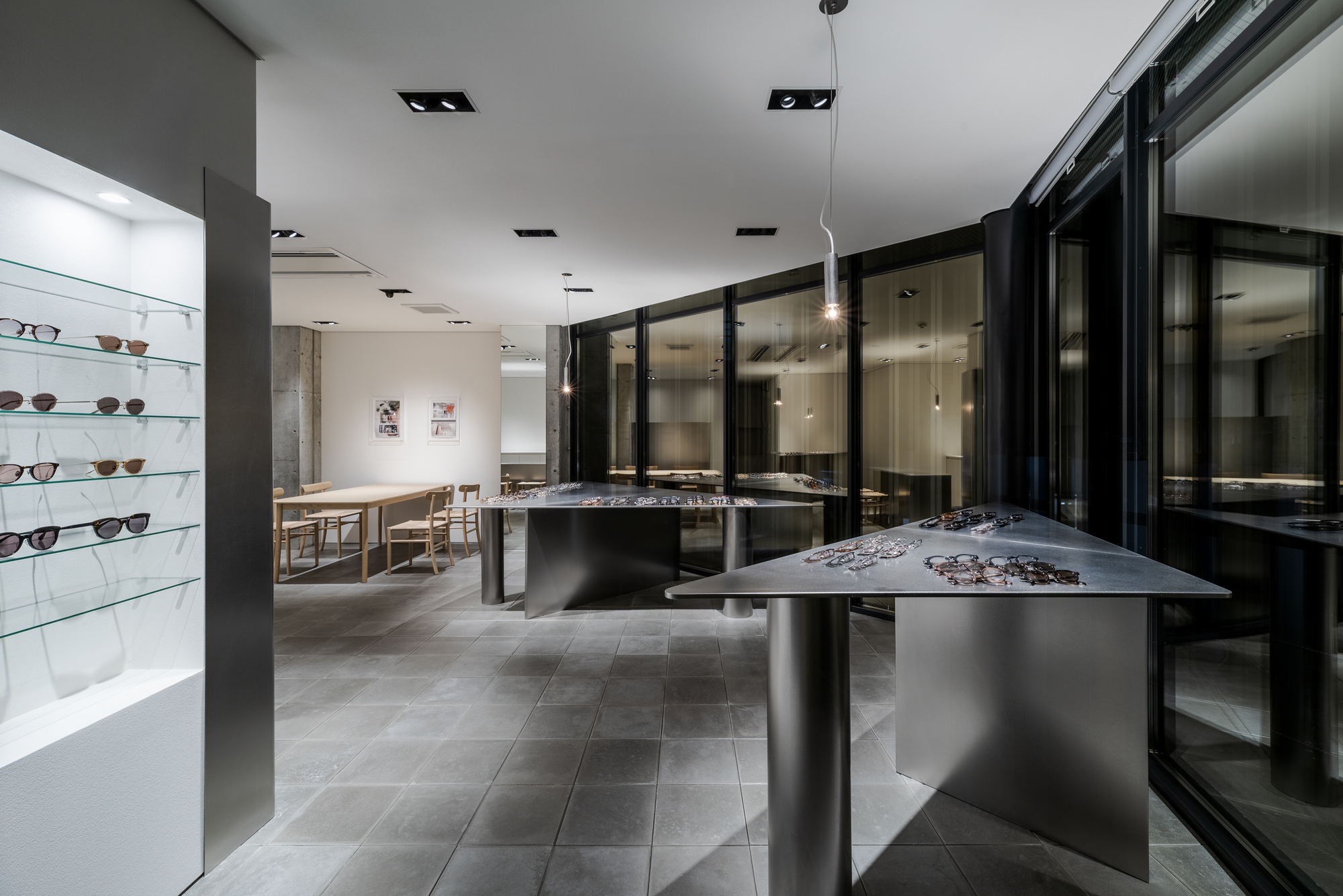 Interior of an eyewear showroom with metal display tables and black-framed glass partitions