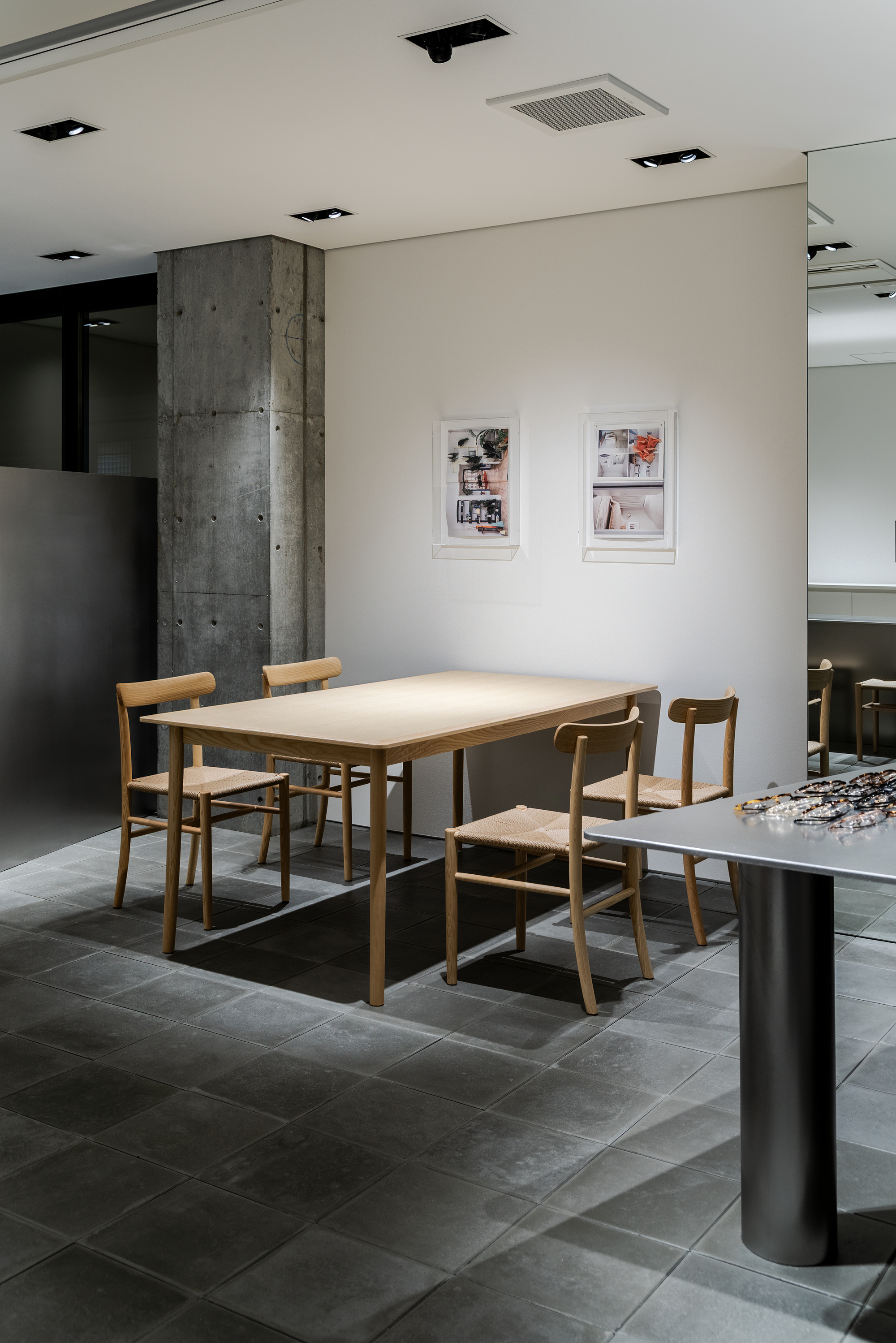 Timber dining table and chairs on grey tile floor beside an exposed concrete column