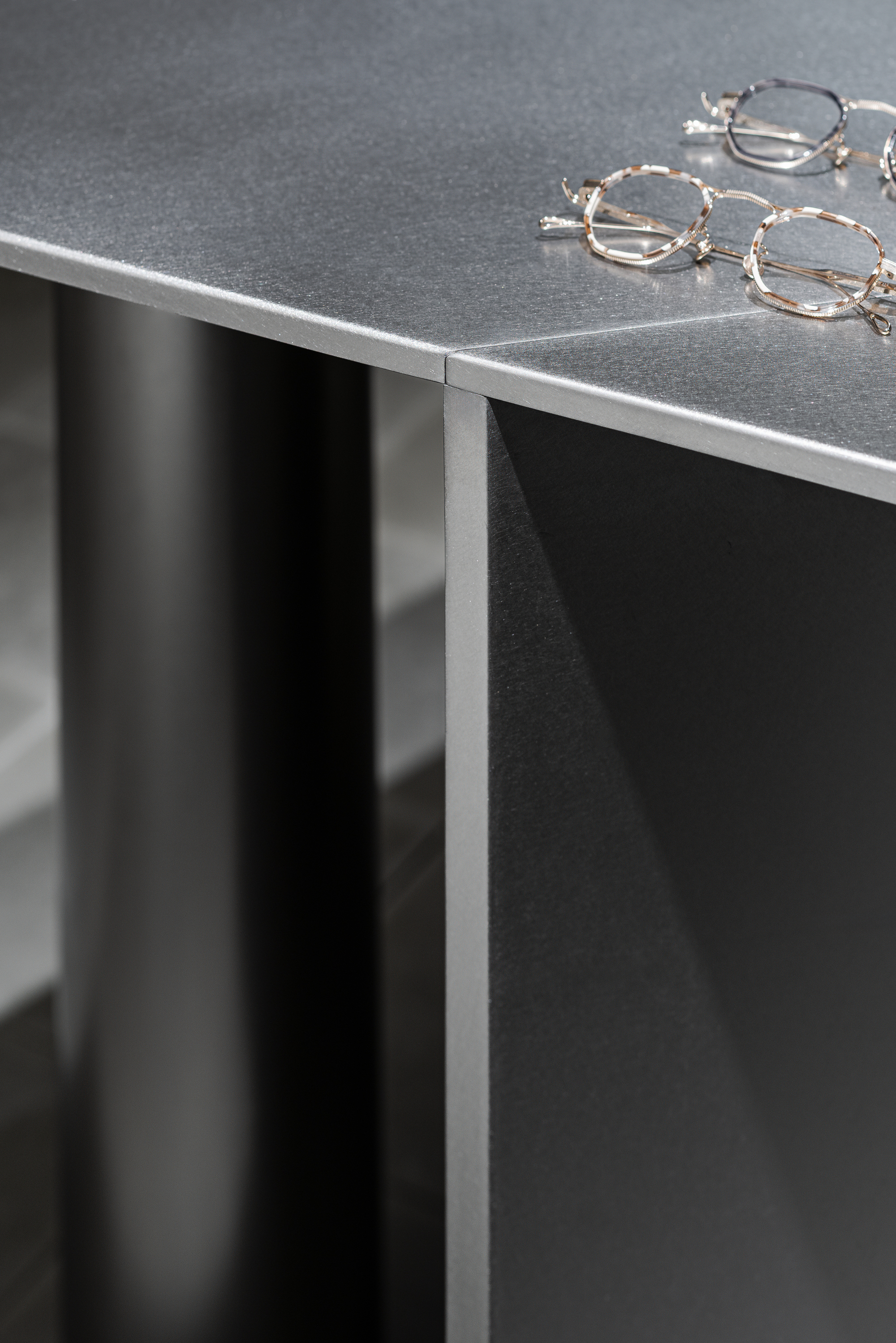 Close-up of the metal edge trim wrapping the black display counter with eyeglass frames