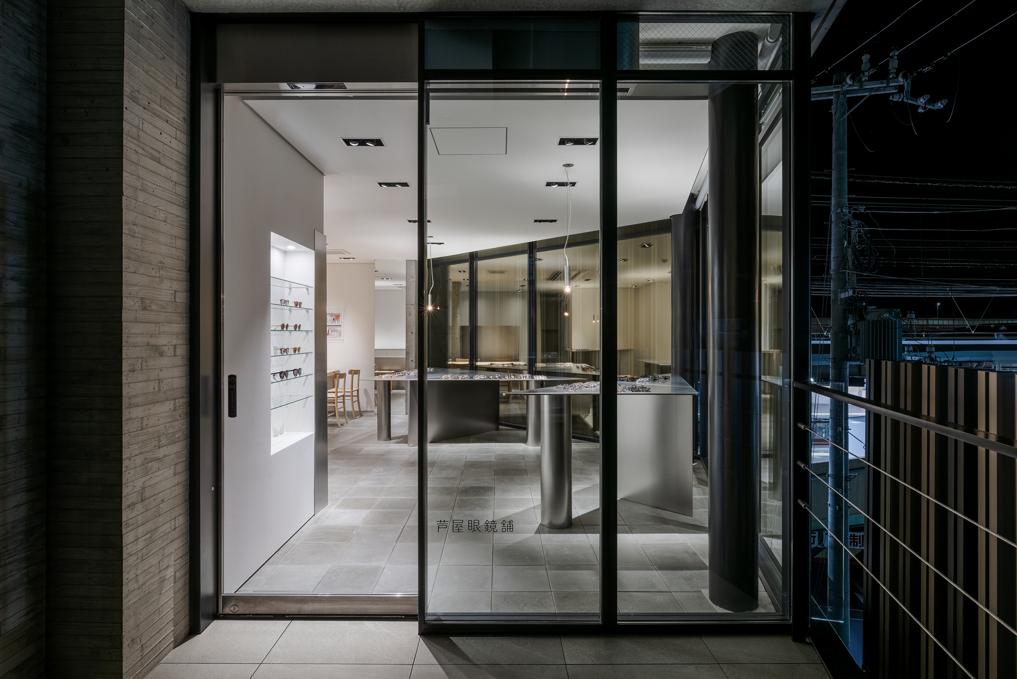 Floor-to-ceiling glass storefront entrance revealing interior display counters and pendant lights