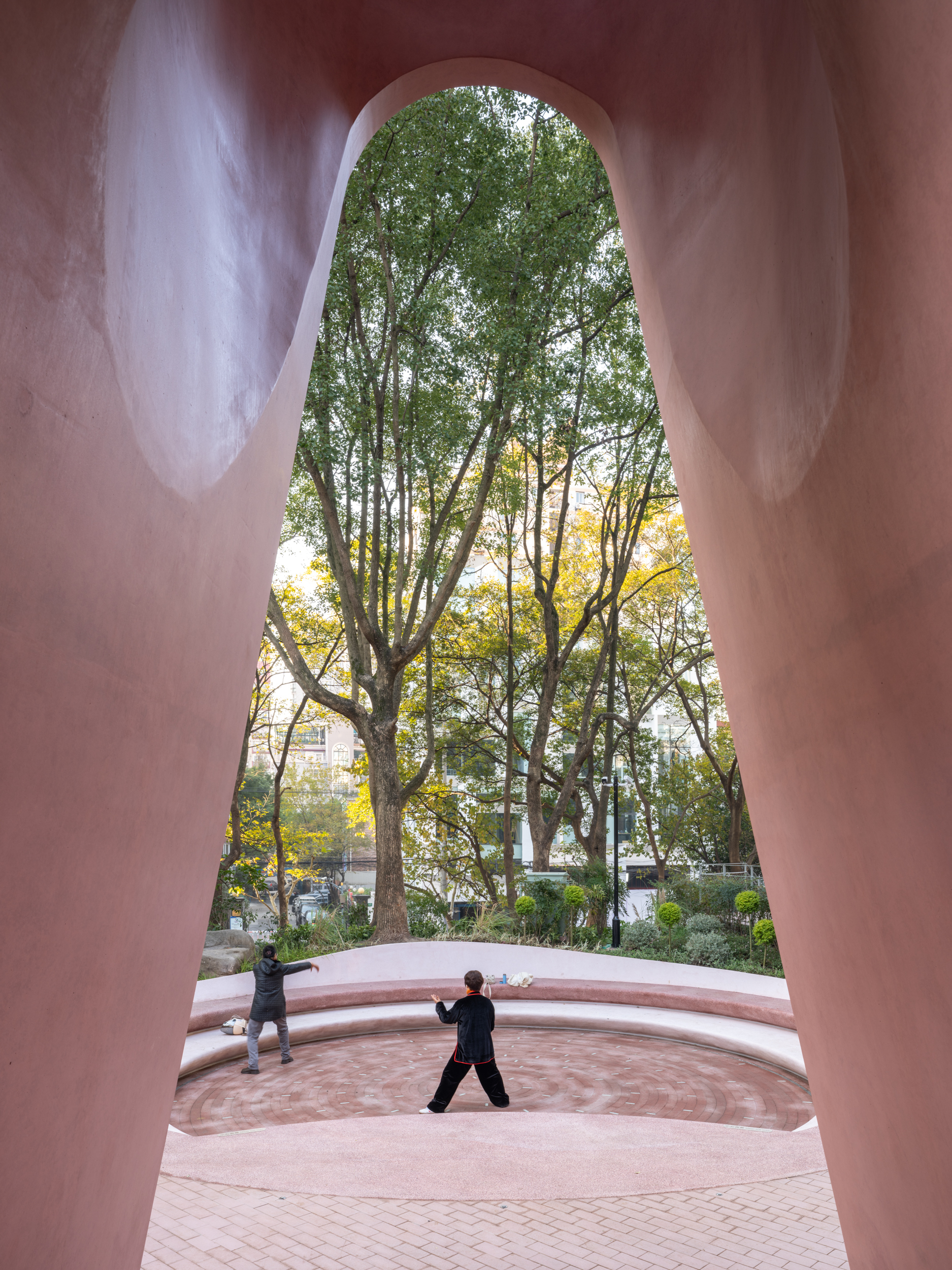 View through the tall arched opening framing a person at the amphitheater with trees beyond