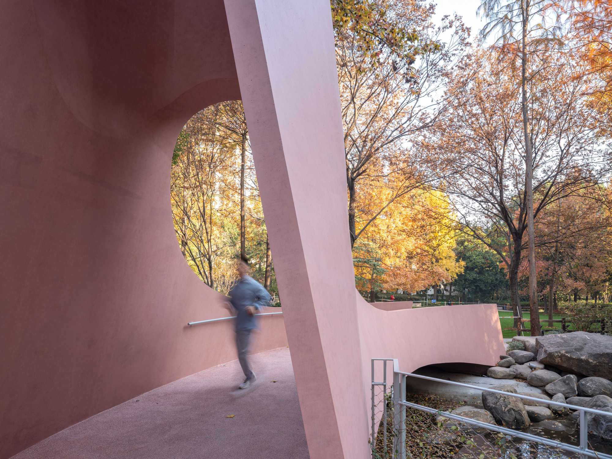 Interior walkway through the gateway with a blurred figure passing beside the curved parapet at dusk