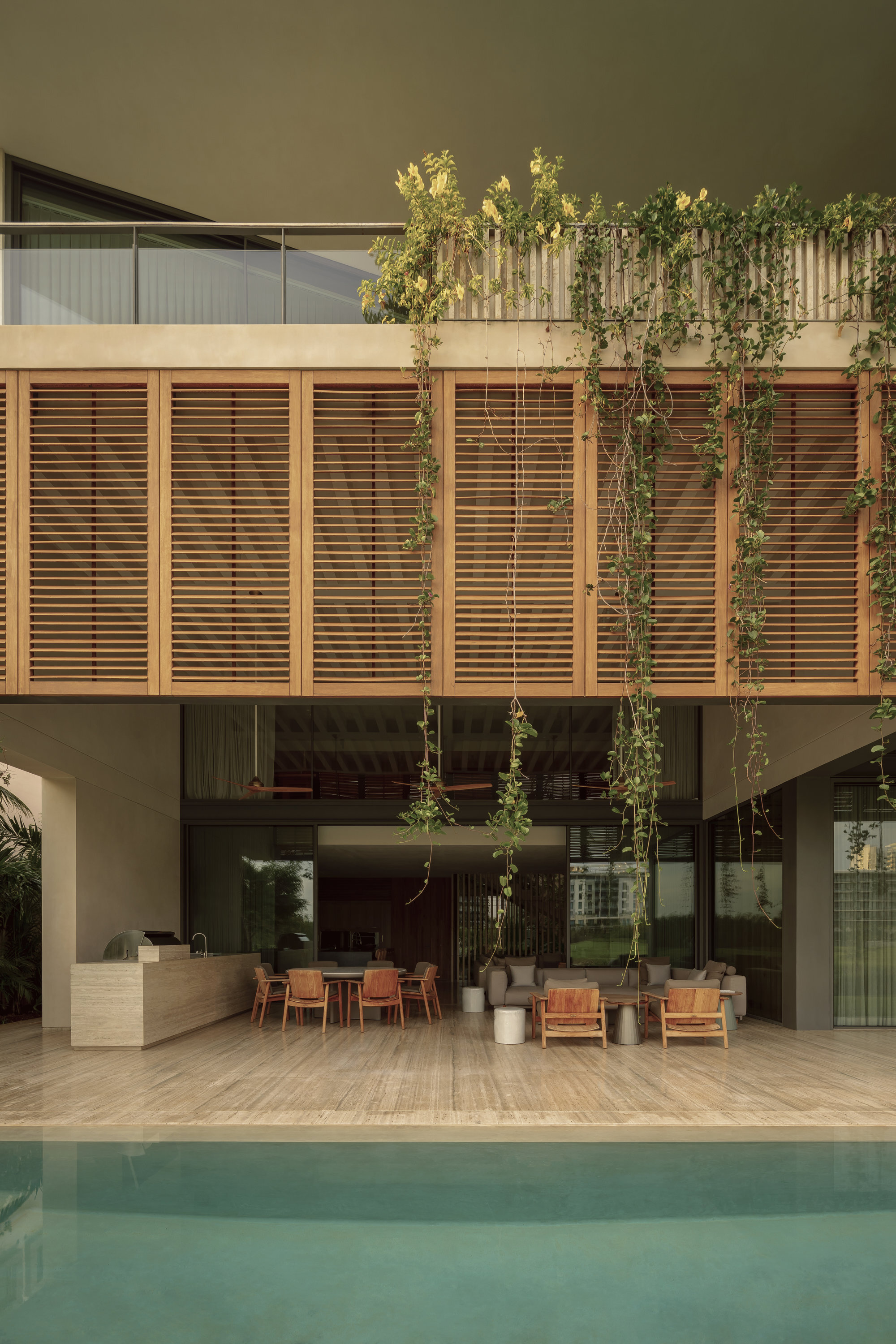 Covered poolside terrace with horizontal timber louver screen and cascading vines overhead