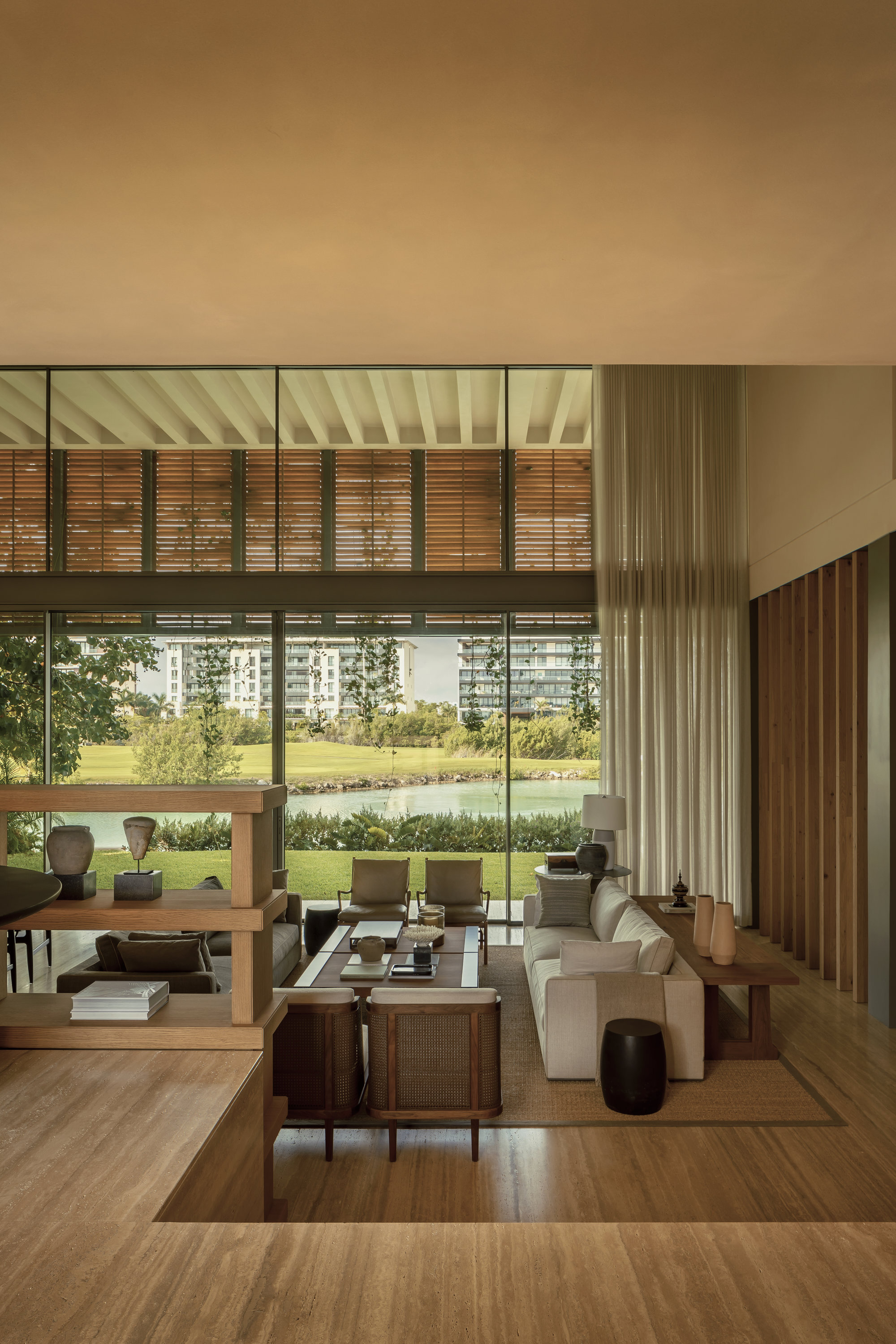 Double-height living space with exposed beam ceiling opening to lawn through timber-screened glazing