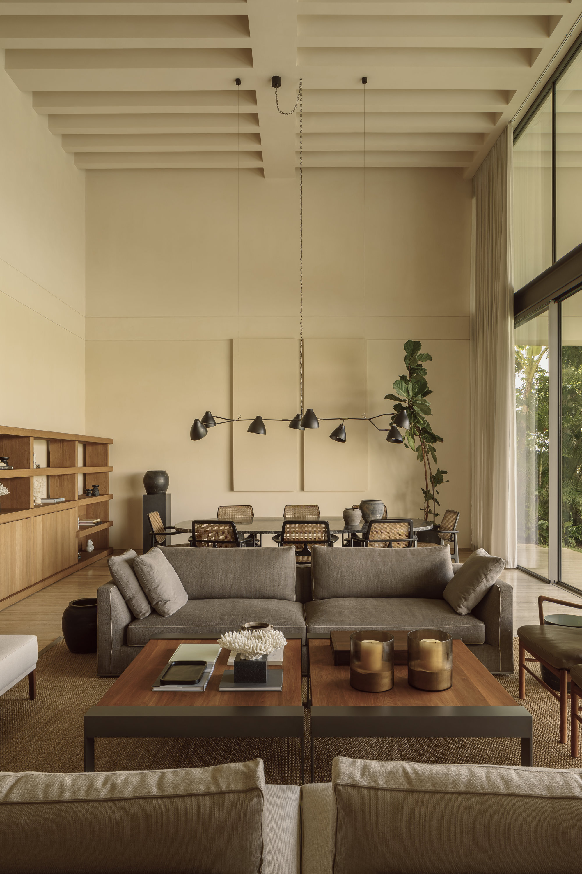 Seating area beneath exposed beam ceiling with linear pendant light and potted fiddle-leaf fig
