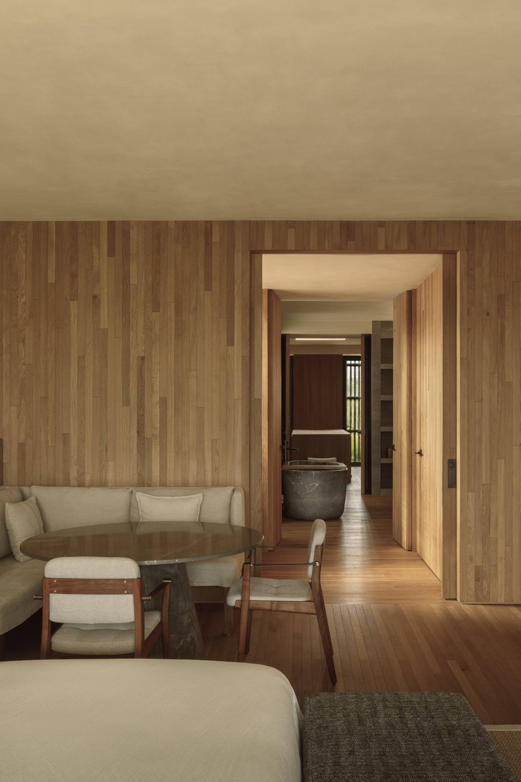 Bedroom with timber-clad wall and view through doorway to corridor and bath beyond