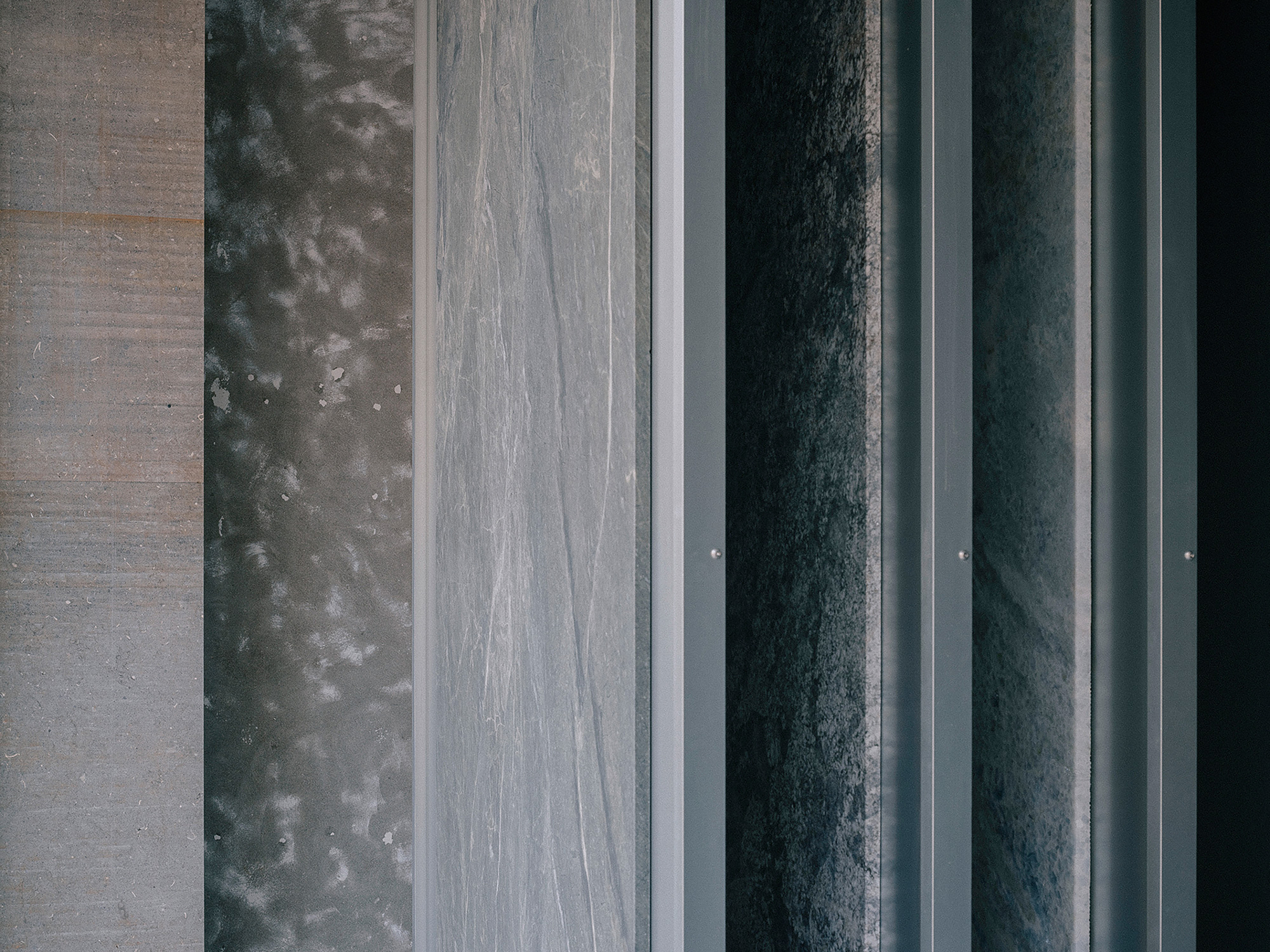 Overhead view of parallel material bands including concrete, dark metal panels and stone pavers