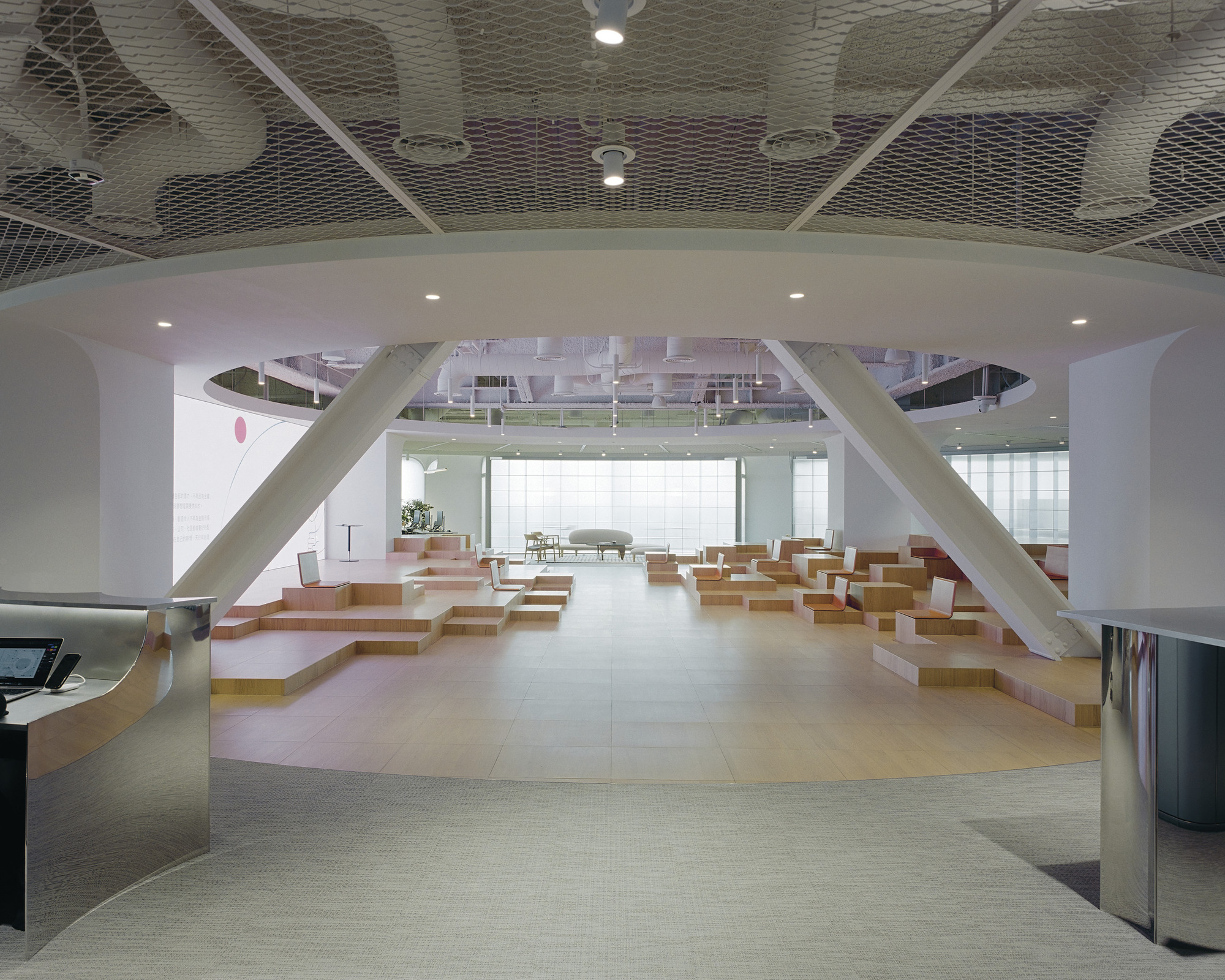 Arched portal framing tiered seating area with diagonal structural beams and metal mesh ceiling
