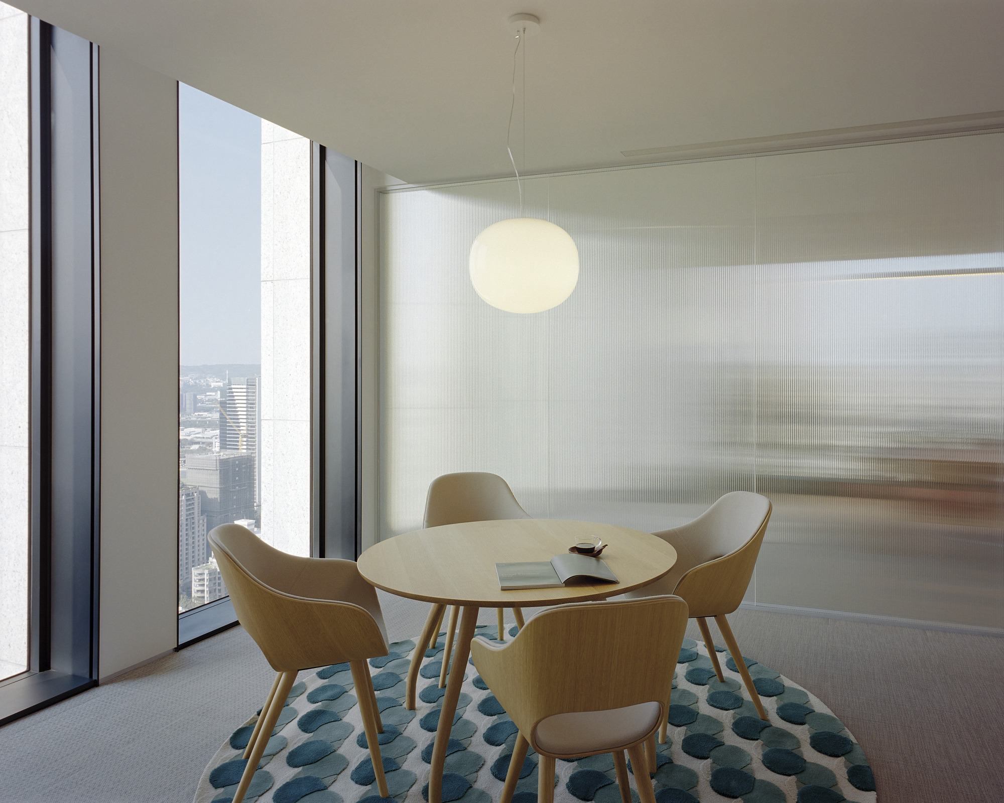 Meeting room with round table and floor-to-ceiling windows overlooking the cityscape