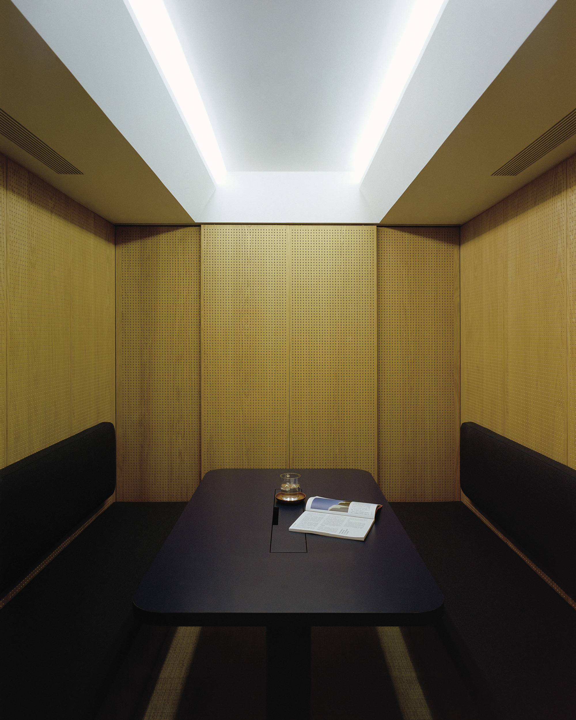 Enclosed booth with woven gold panels and recessed ceiling illumination