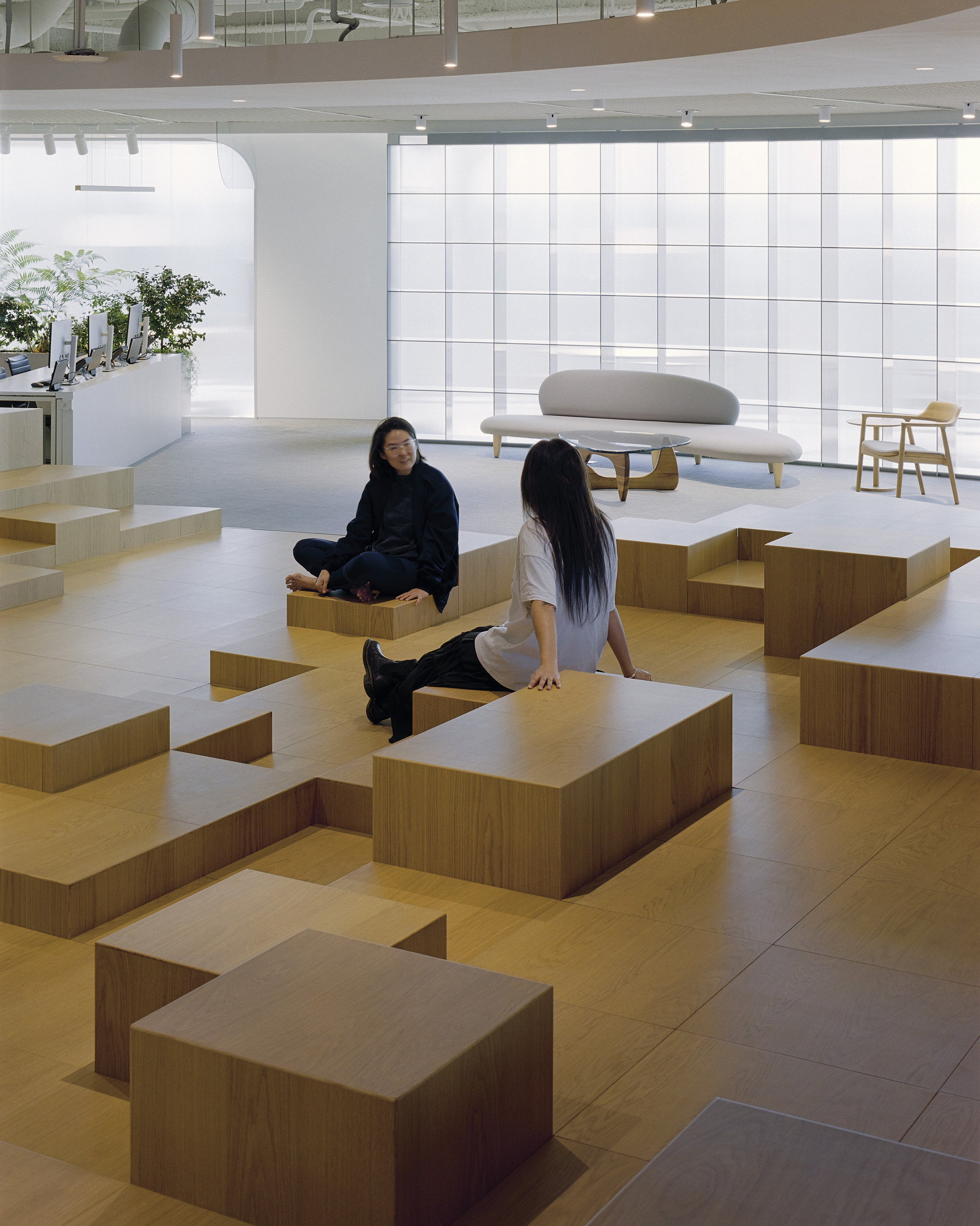 Lobby seating area with stepped timber blocks and two visitors