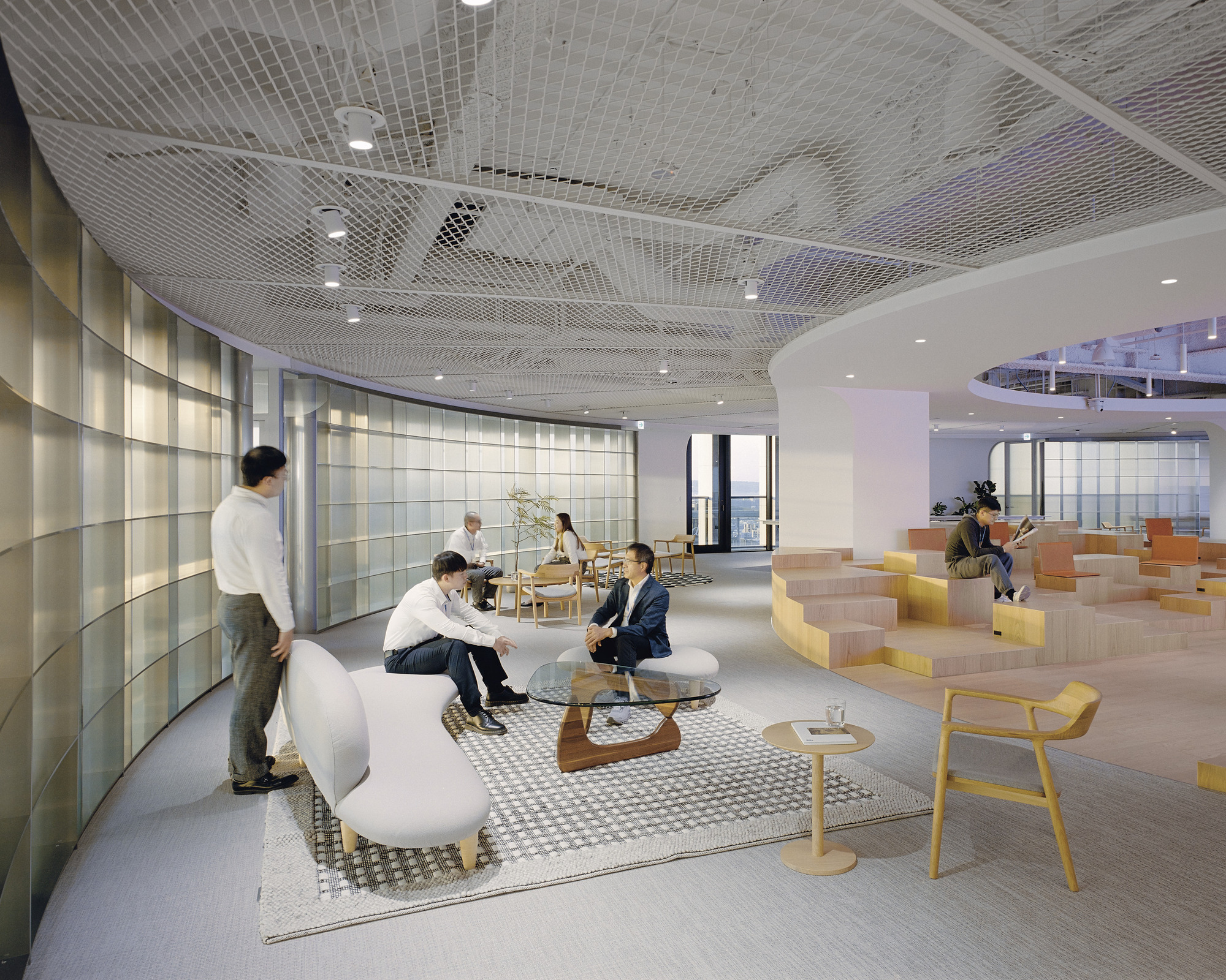 Open office lounge with mesh ceiling and stepped seating platform in use