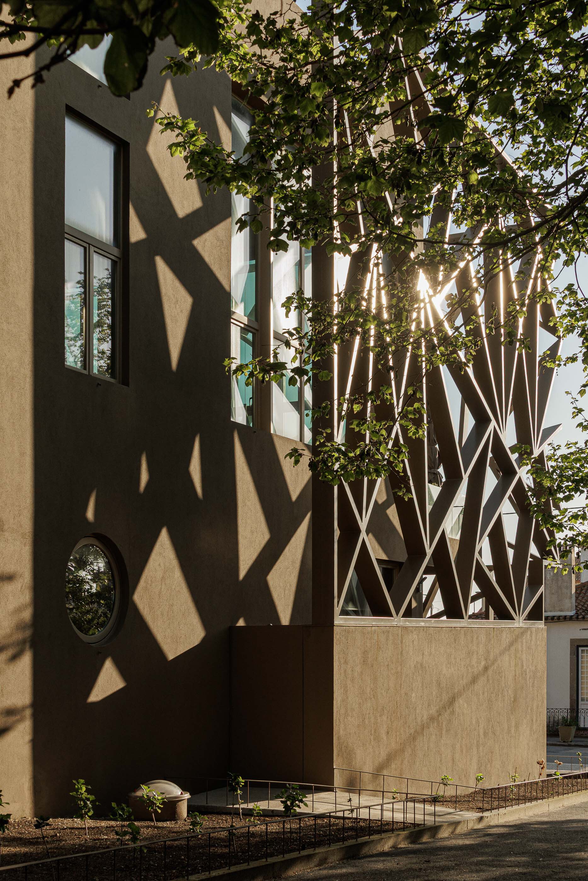 Late afternoon sunlight filtering through the lattice structure and casting geometric shadows on the plaster wall